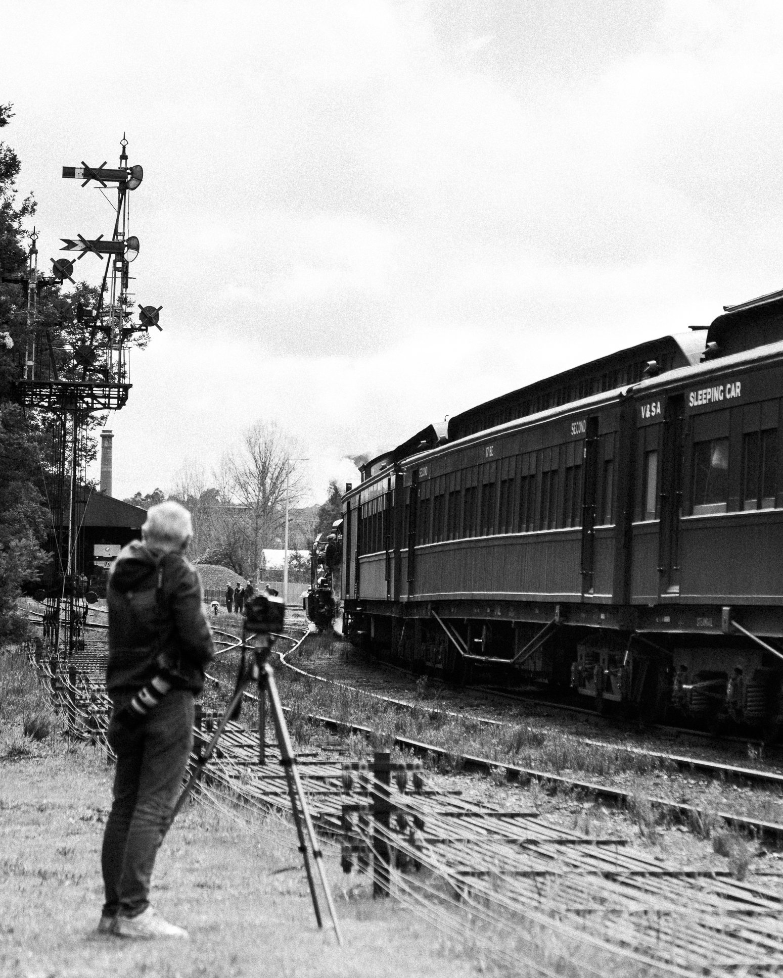 A Photographer watches a steam train shunting at Castlemaine on the Victorian Goldfields Railway with mechanical signals and point rodding in the foreground. Scott Gould A Railway Life Photography