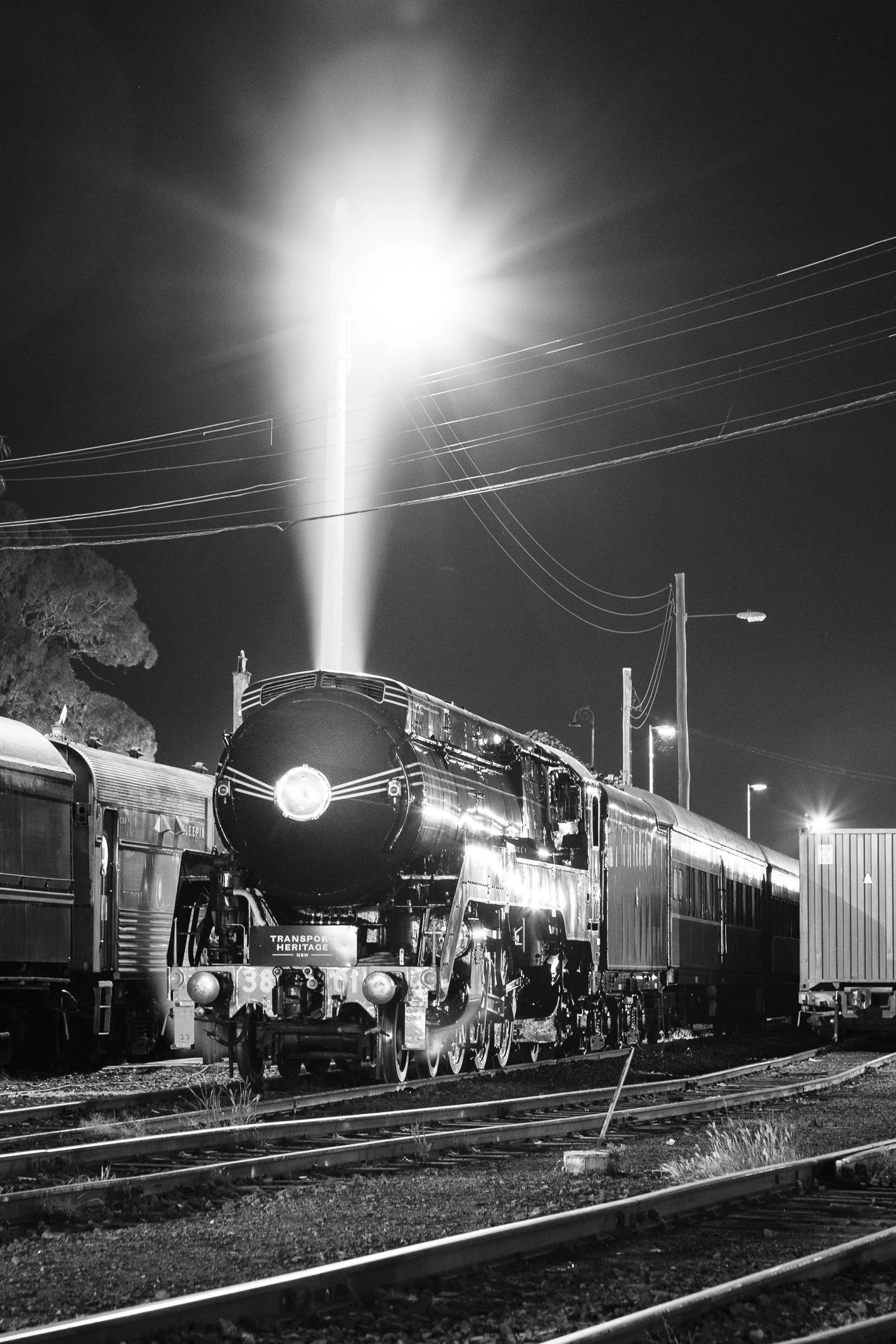 Steam loco 3801 at rest in Junee yard with a tall plume of exhaust steam rising. Black and white Scott Gould A railway life photography