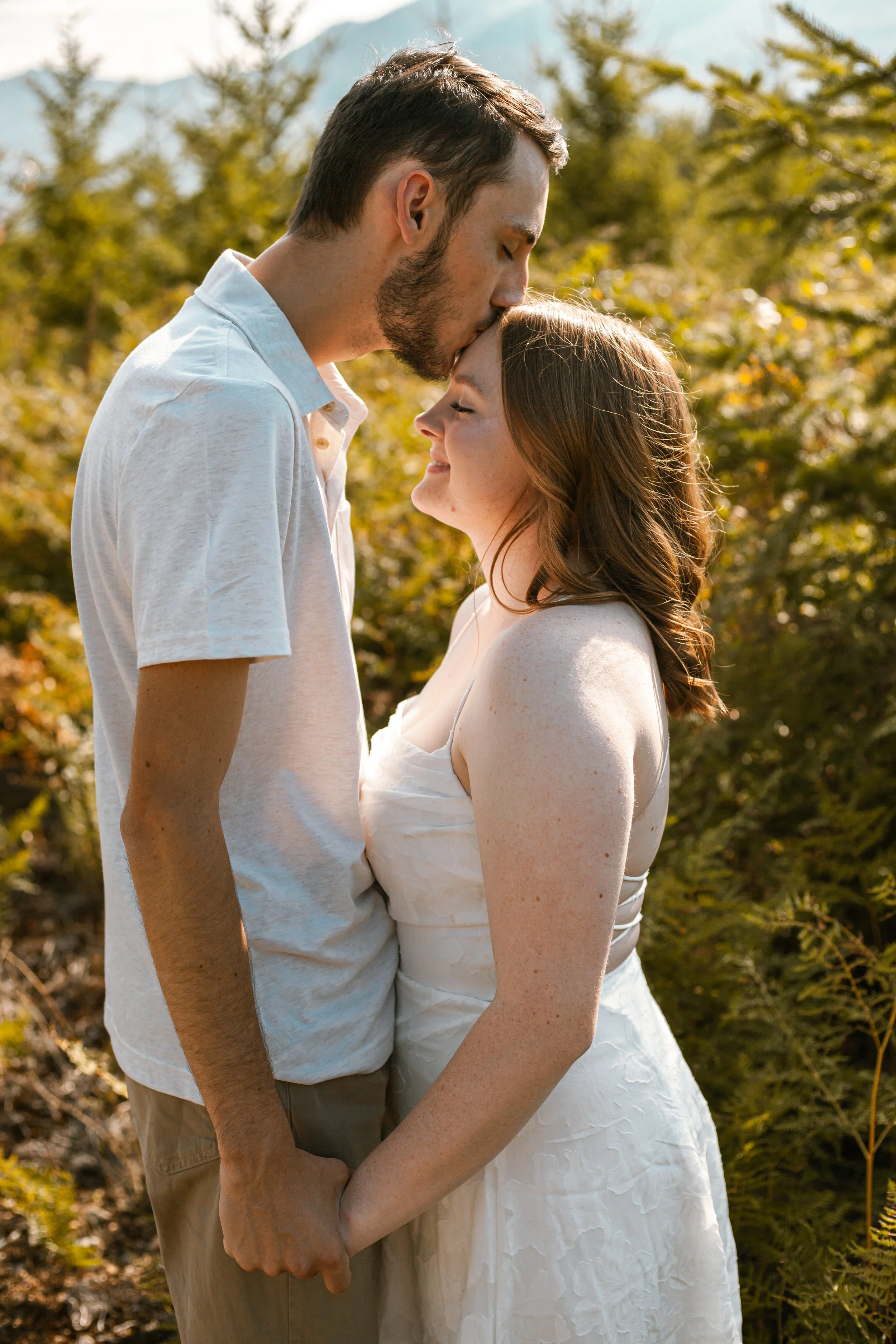 An engaged couples stands posed in front of a foresty background located in rural Snohomish County, WA.