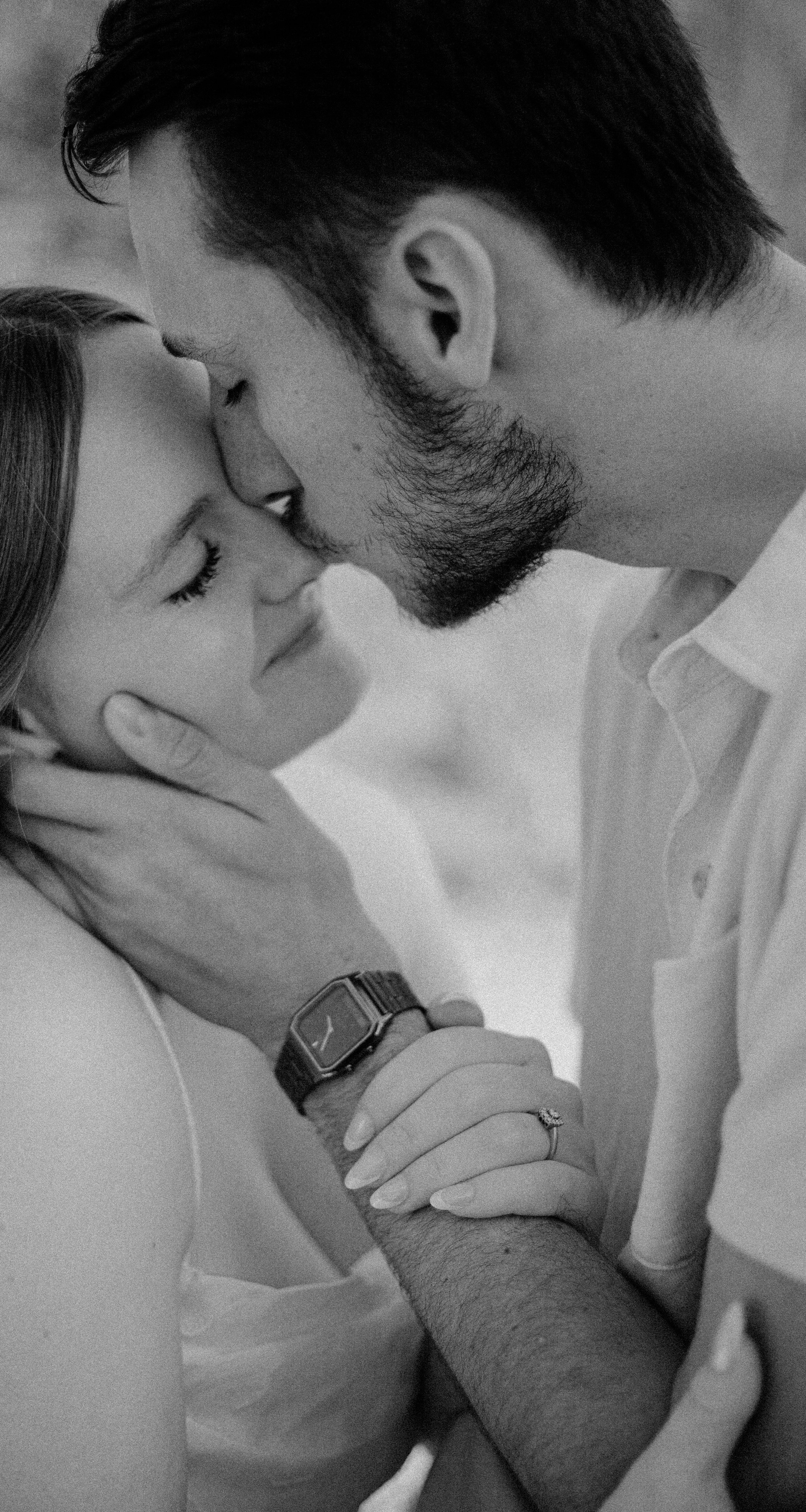 Smiling woman with short black hair in a blue top, standing in a greenhouse with green foliage in the background.