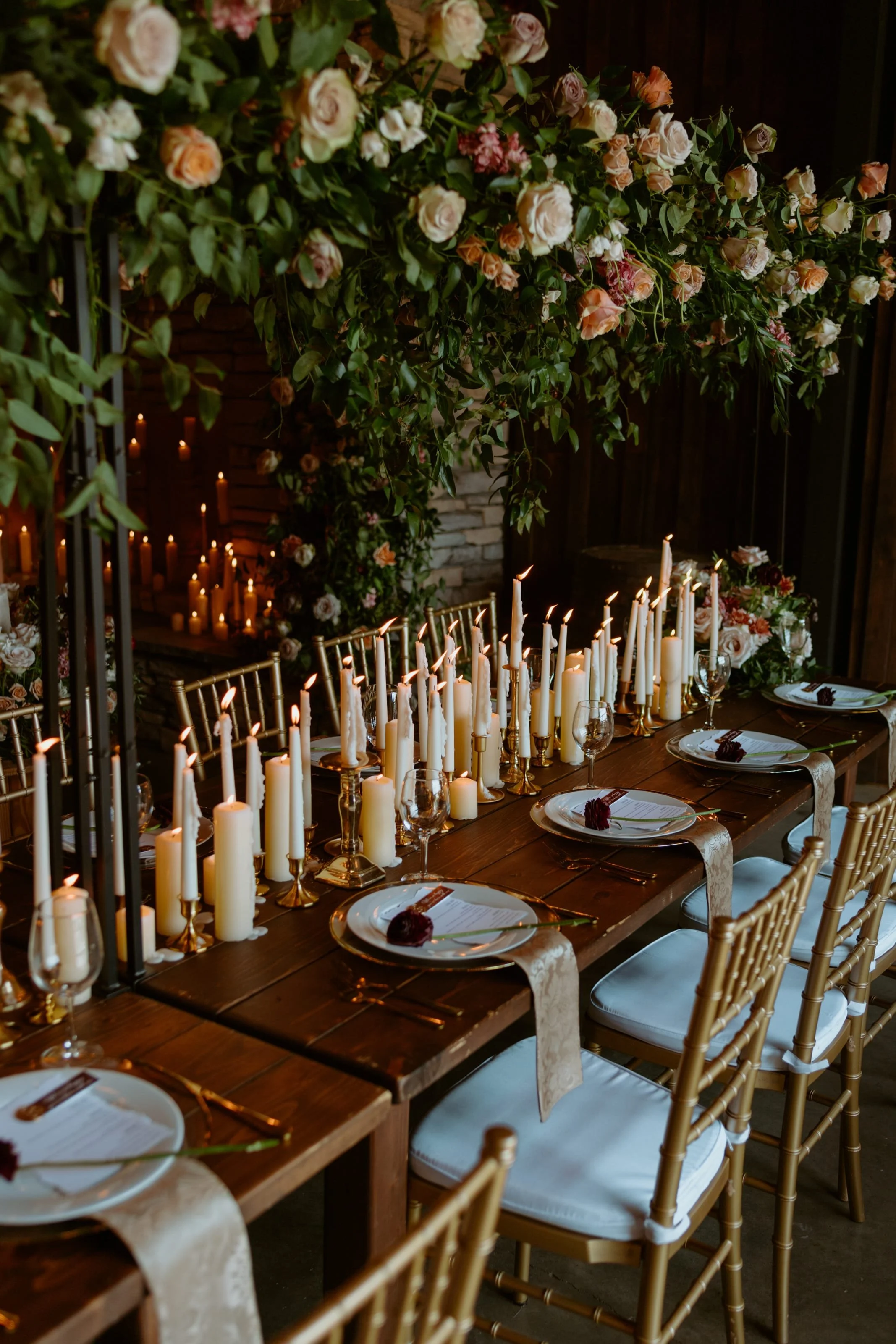 A romantic dining table decorated with numerous white candles, set for a special occasion, with floral arrangements and elegant place settings.