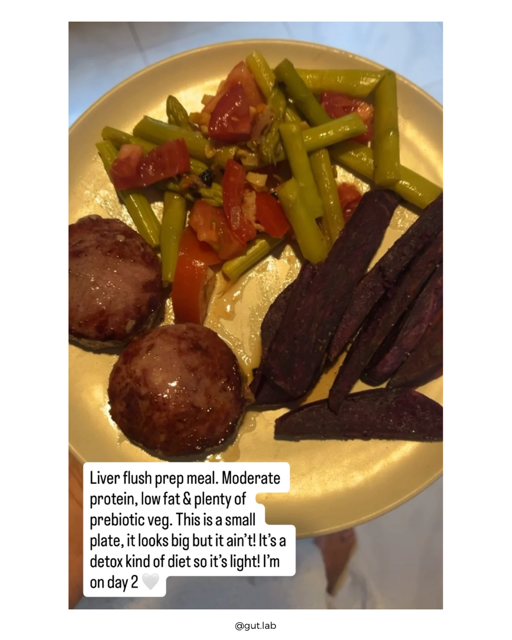 Plate with cooked green beans, chopped tomatoes, two meatballs, and cooked purple sweet potatoes.