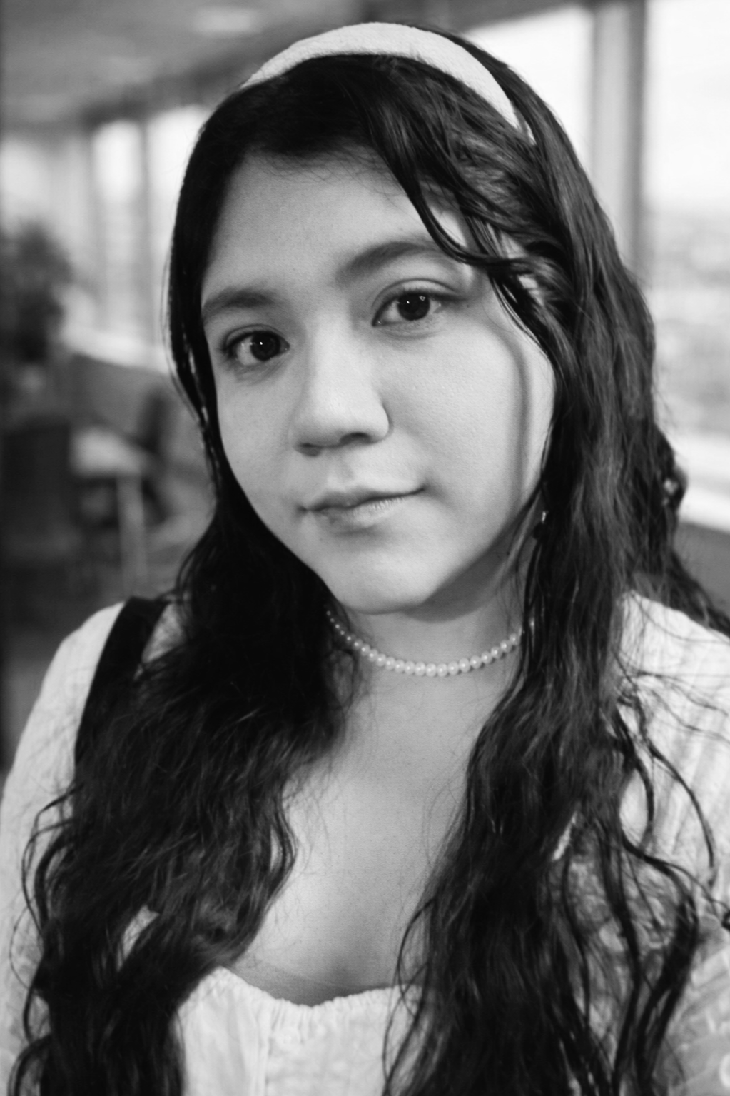 A woman taking a selfie in a dimly lit venue with brick walls and other people in the background.