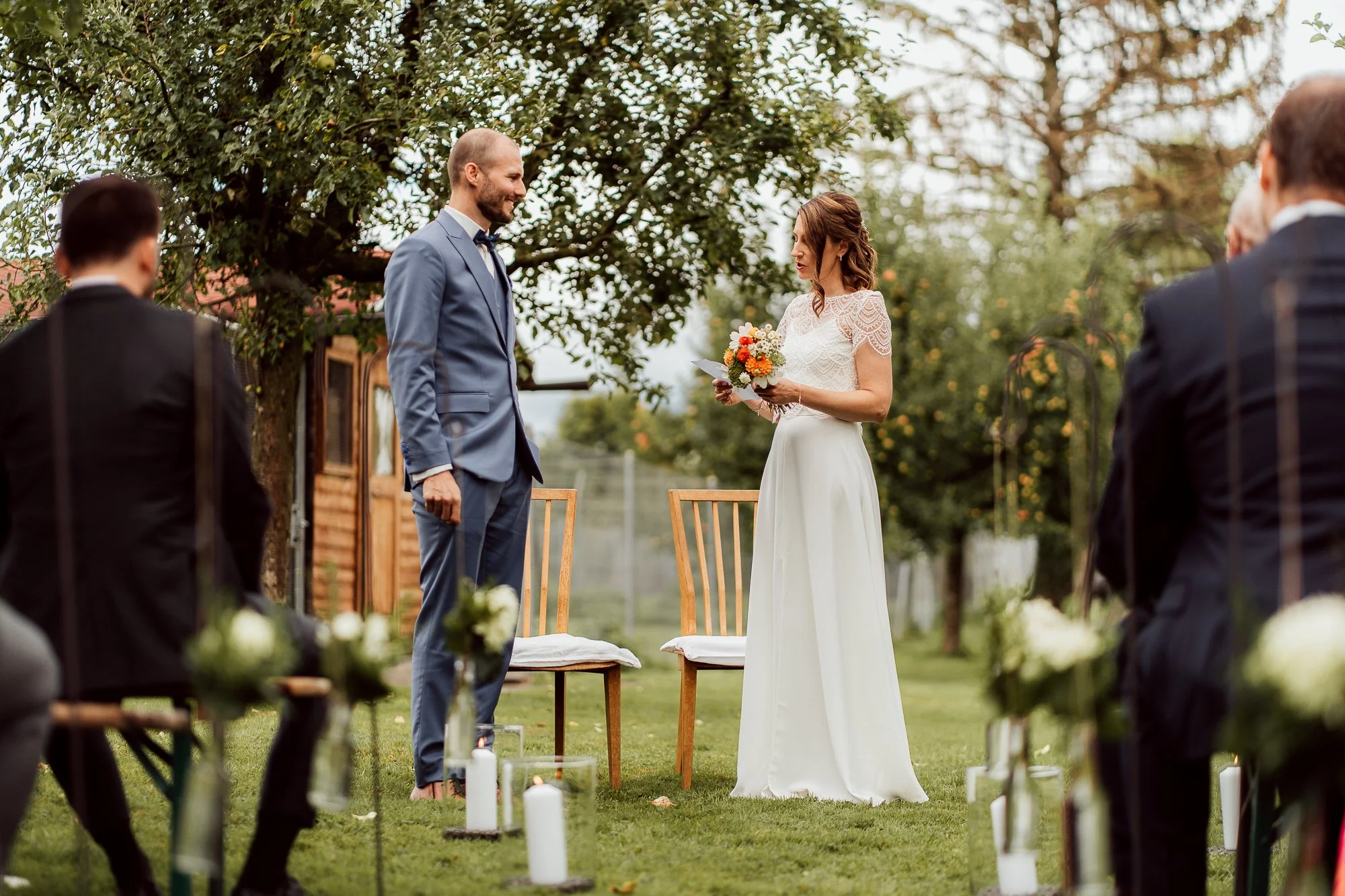 Ein Brautpaar bei einer Hochzeit im Freien, umgeben von Gästen und Kerzen auf dem Rasen I Hochzeitsfotografie Luzern