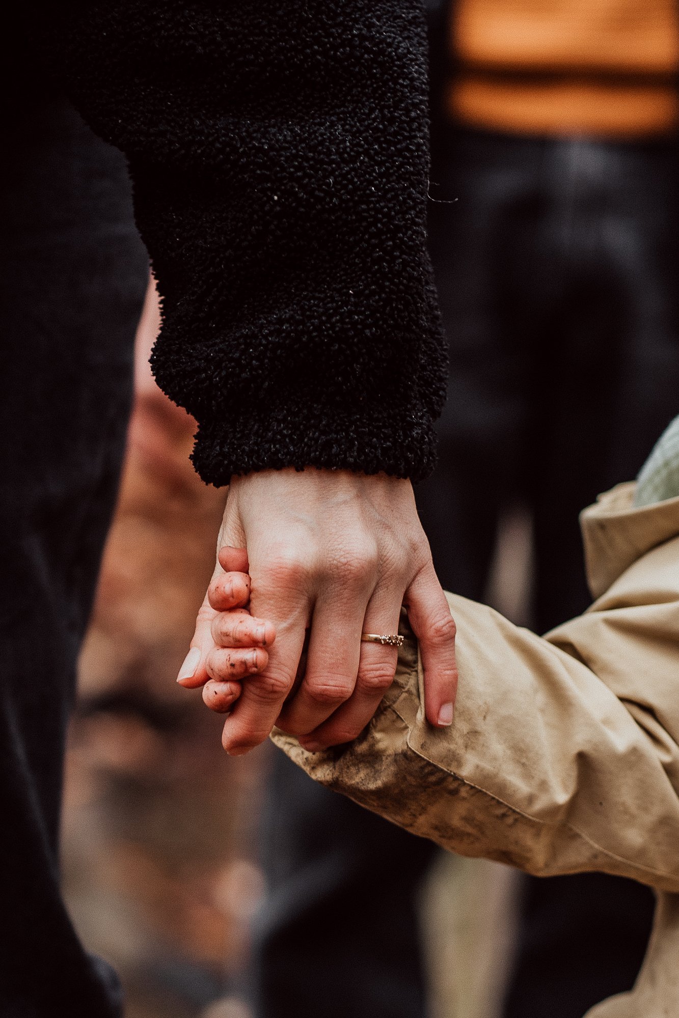 Zwei Personen halten sich an den Händen fest, der Hintergrund ist verschwommen I Familienfotografie Luzern