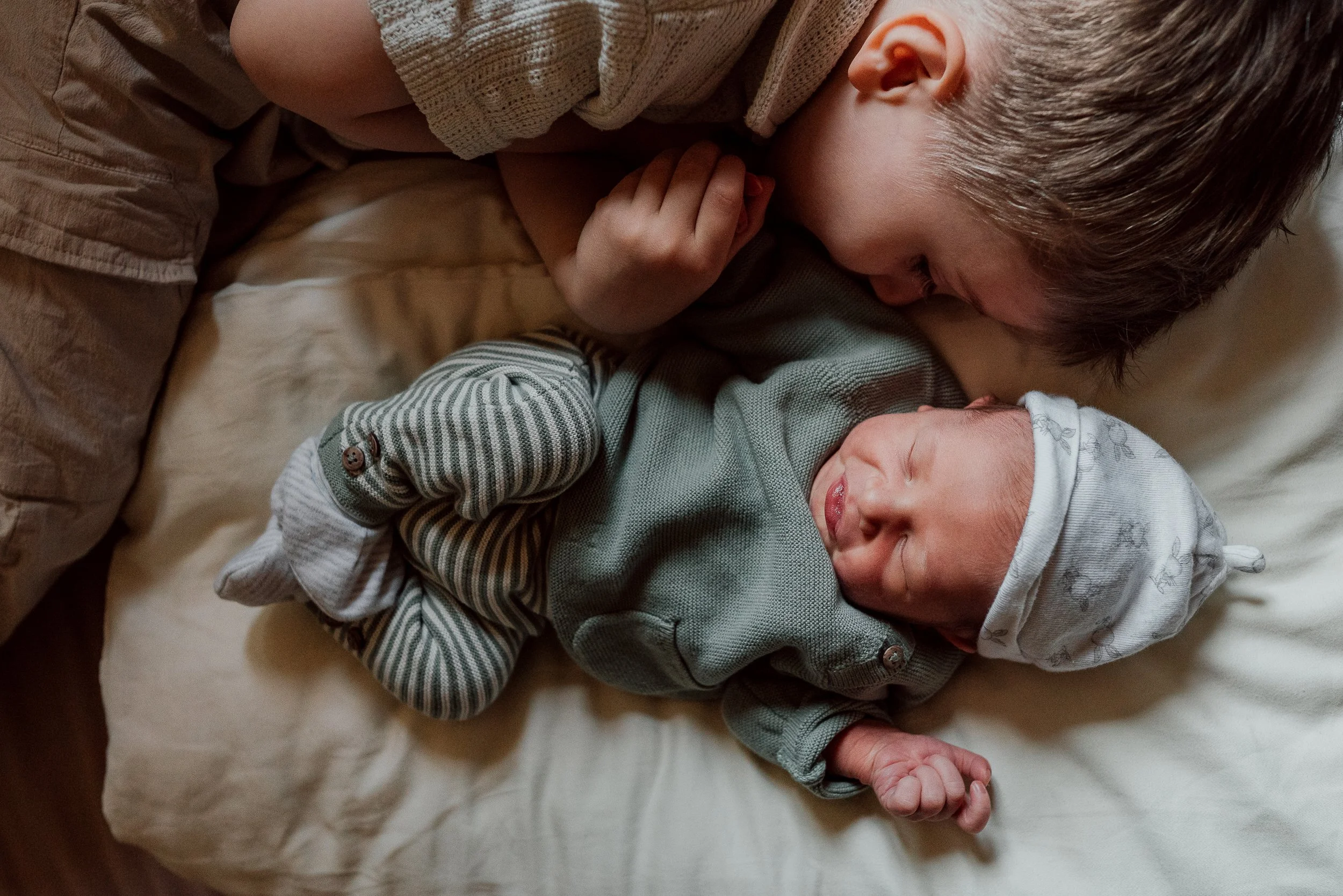 Baby liegt mit Bruder auf dem Bett I Wochenbettreportage im Geburtshaus Terra Alta I Céline Mettler