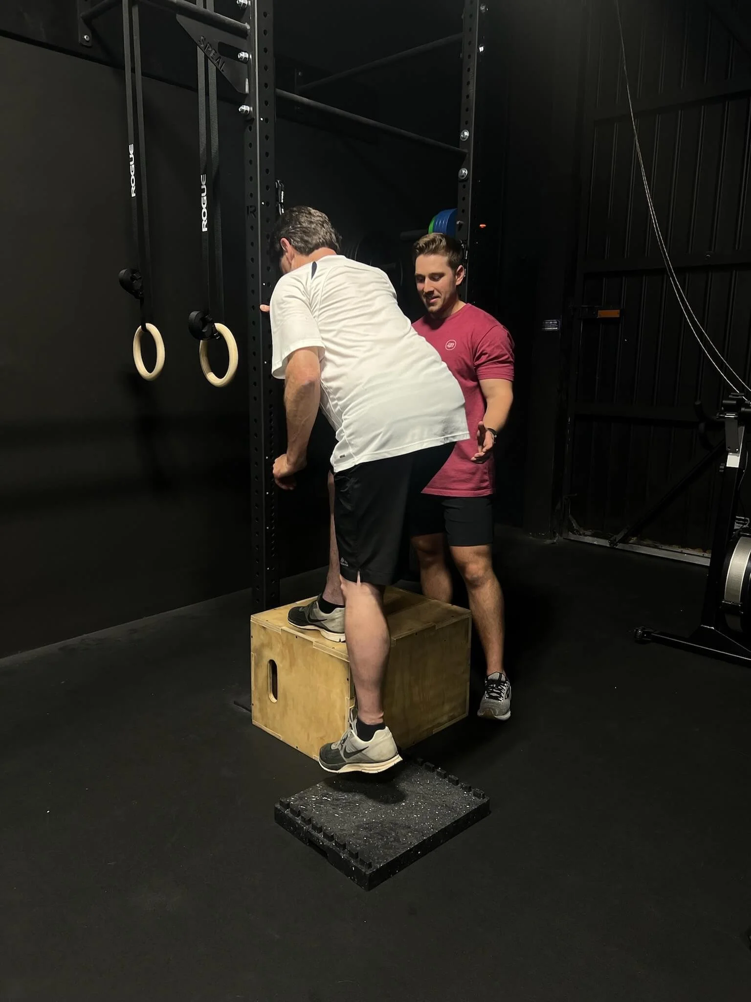 A older gentleman with knee pain and arthritis performing a box step up during his physical therapy session to strengthen his lower body.