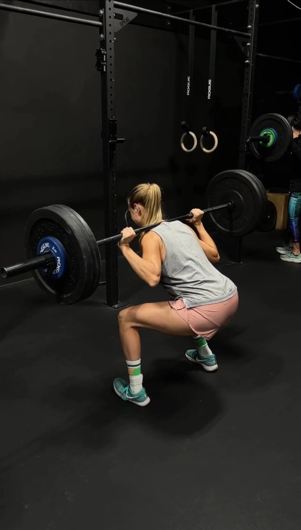 A young female athlete and recreational soccer player performing a back squat with a barbell.