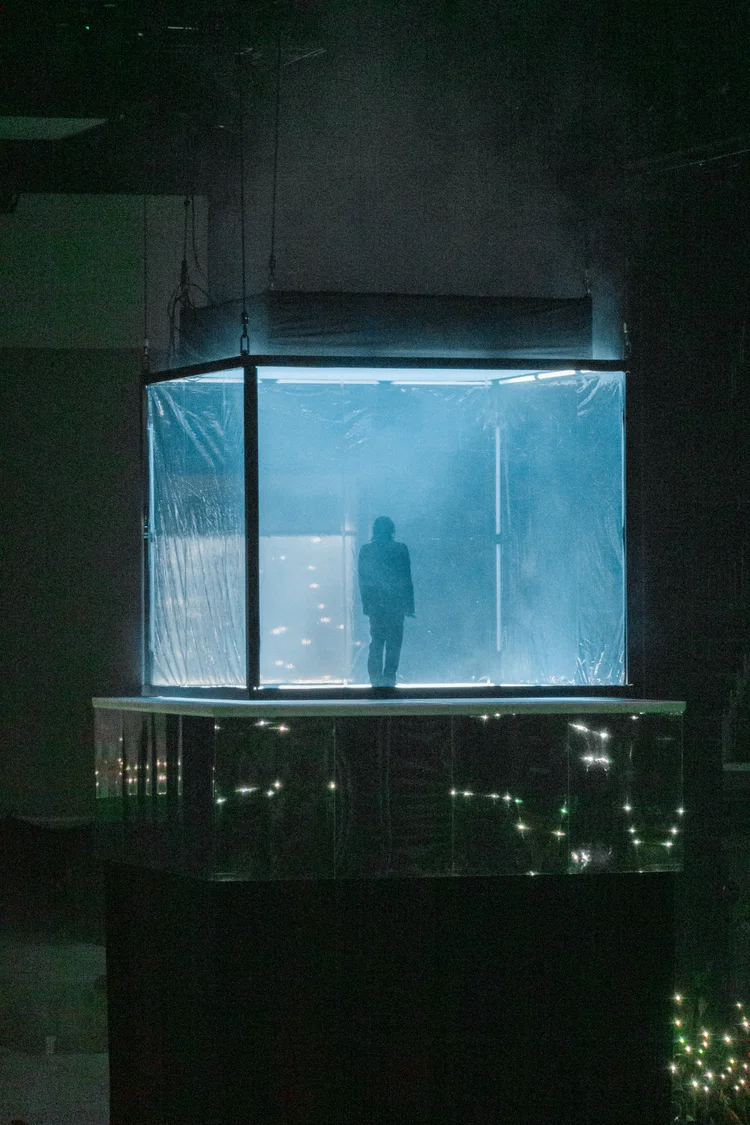 Performer in a blue-lit cube