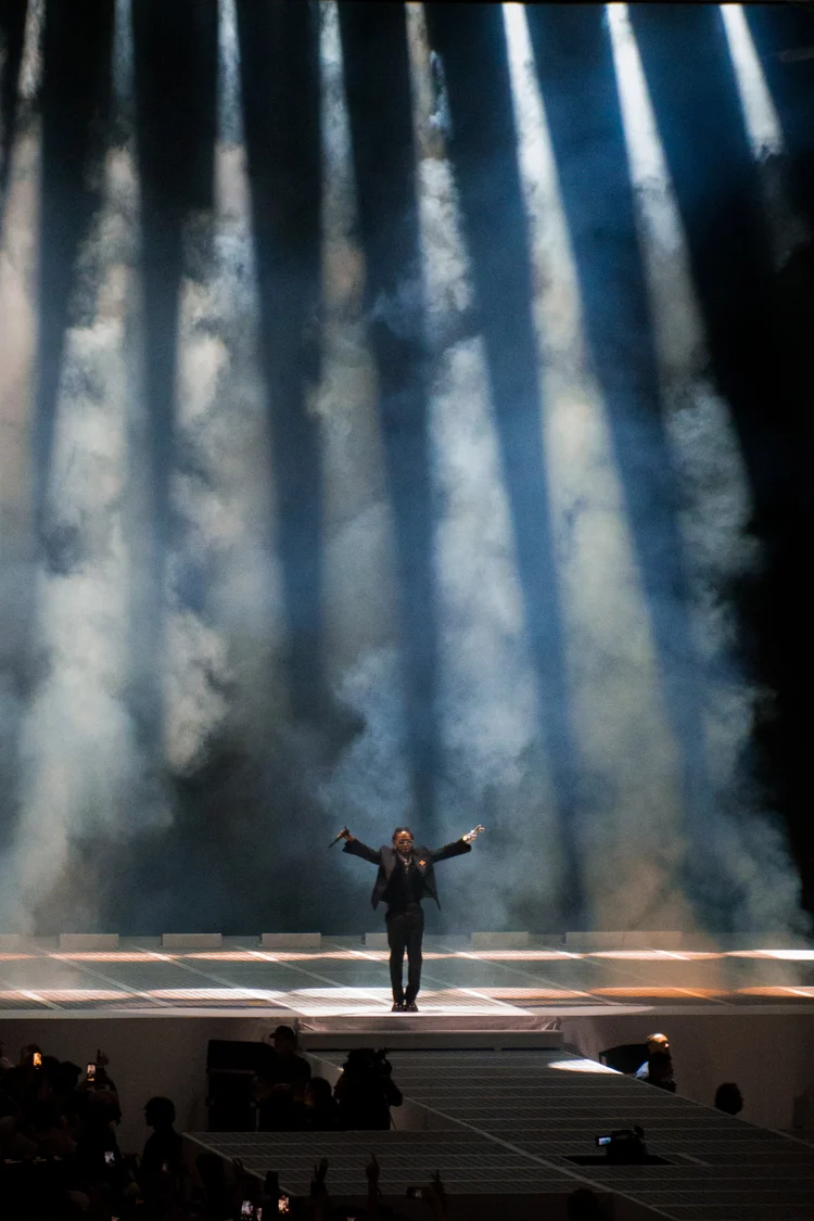 Performer with arms outstretched under spotlights