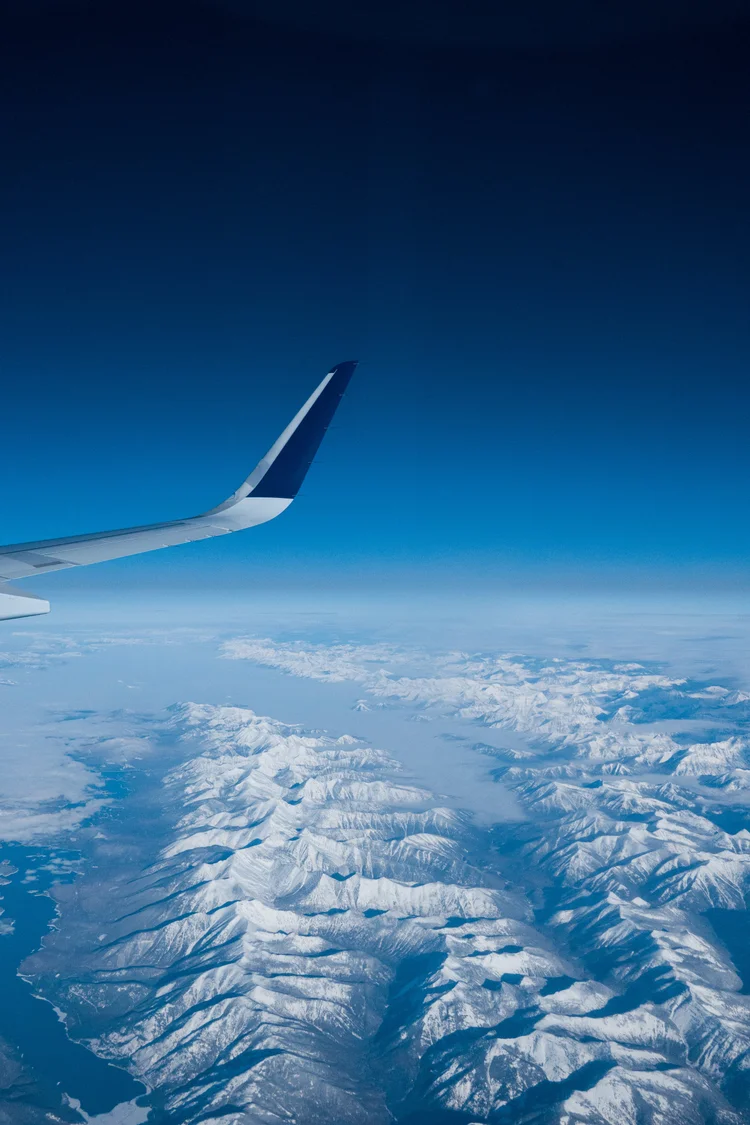 Airplane wing above snowy mountains