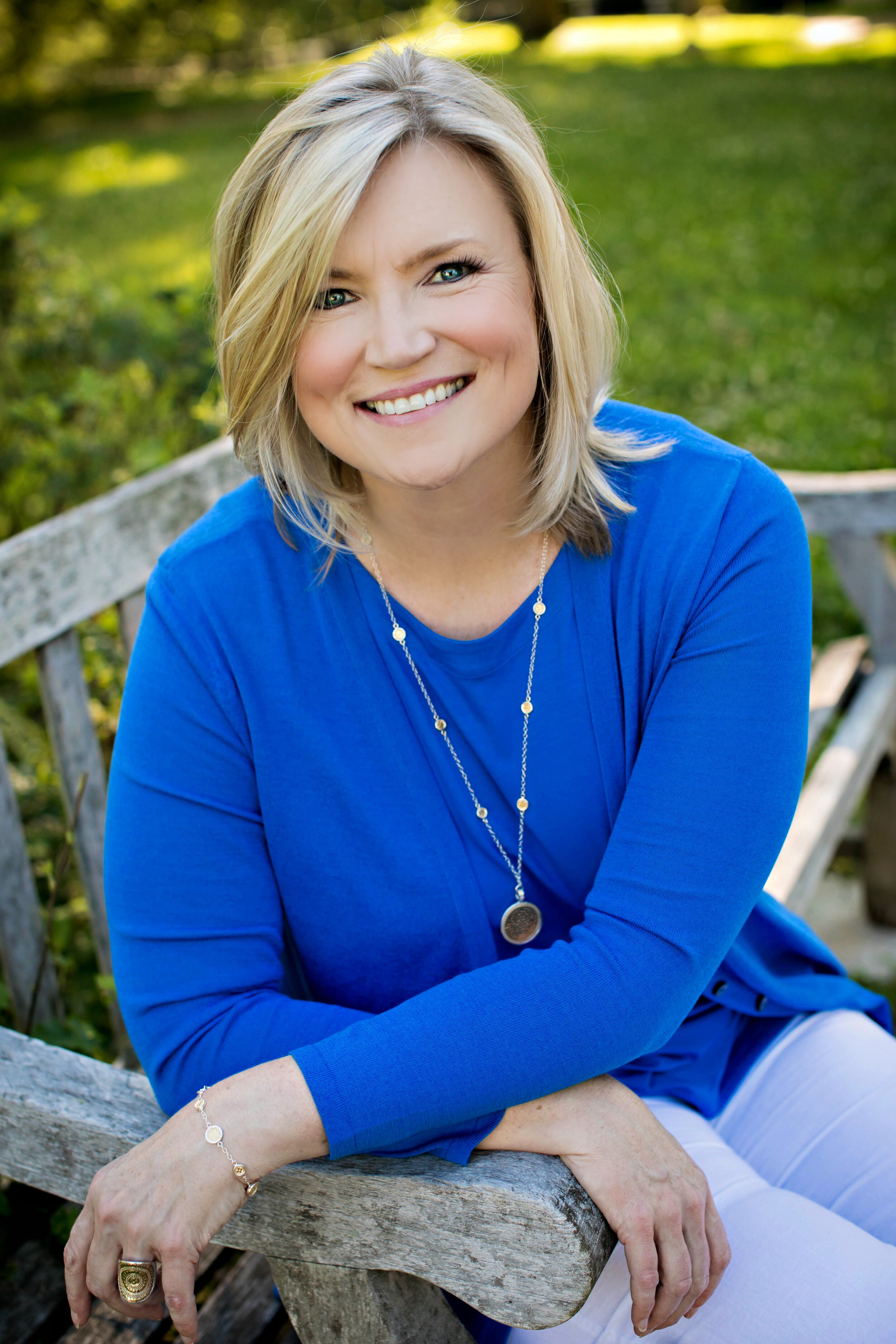 Arianne Rice, facilitator, coach & priest, sitting on a bench, smiling