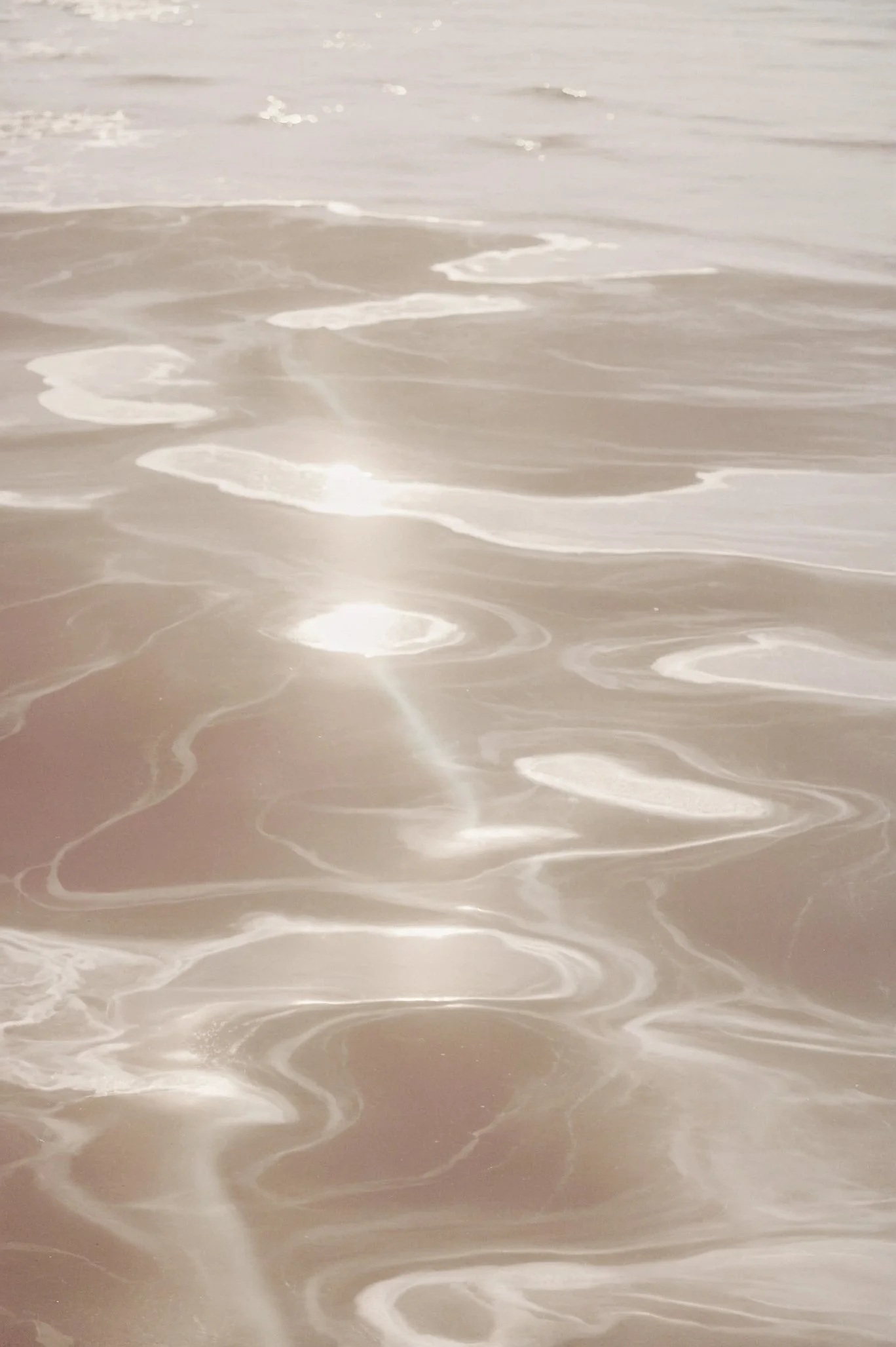 Close-up of gentle ocean waves and foam on sandy beach