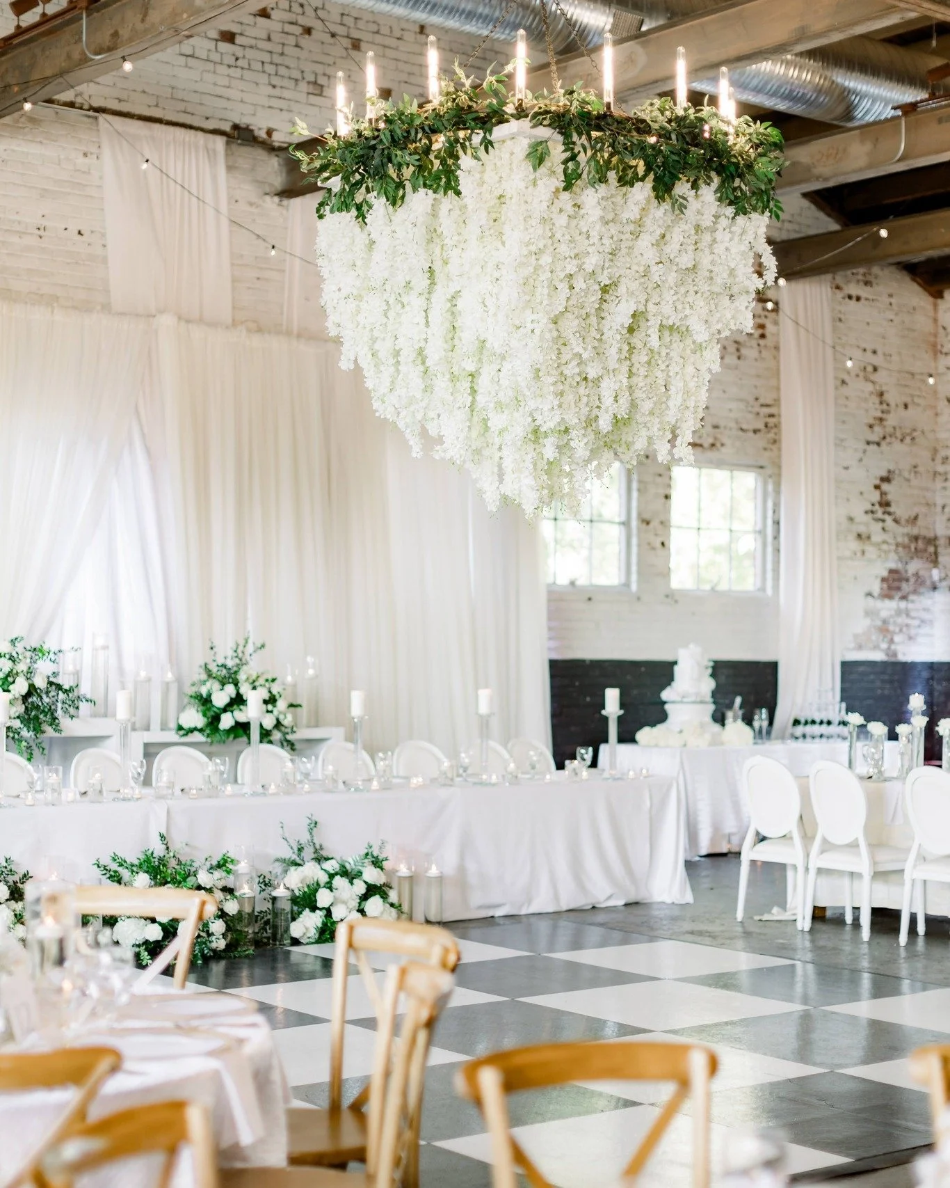 White, cream, and green filled the space with a timeless kind of beauty. 

 Within the restored 1920s walls of The Raymond, candlelight flickered across textured brick, soft drapery, and a checkered dance floor that brought the perfect contrast to th