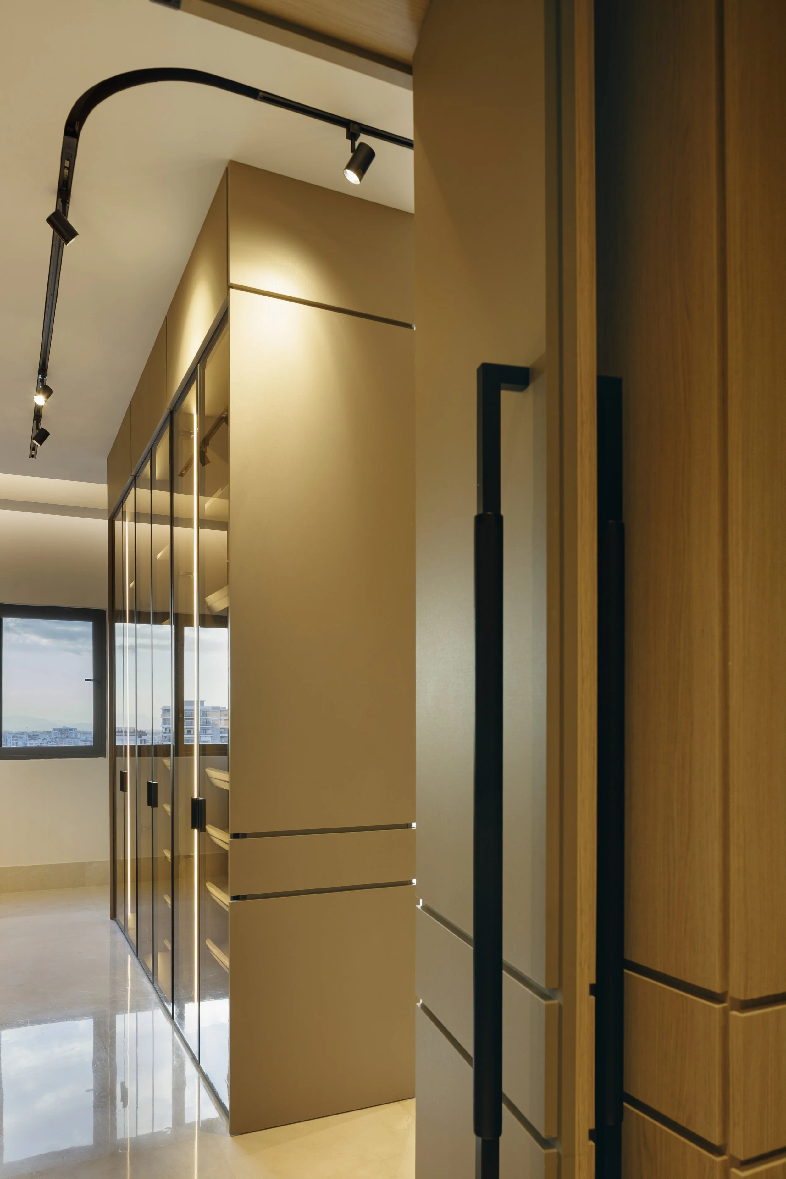Vista de una habitación con armarios de madera y puertas de vidrio, una ventana y una vista de edificios en el exterior.