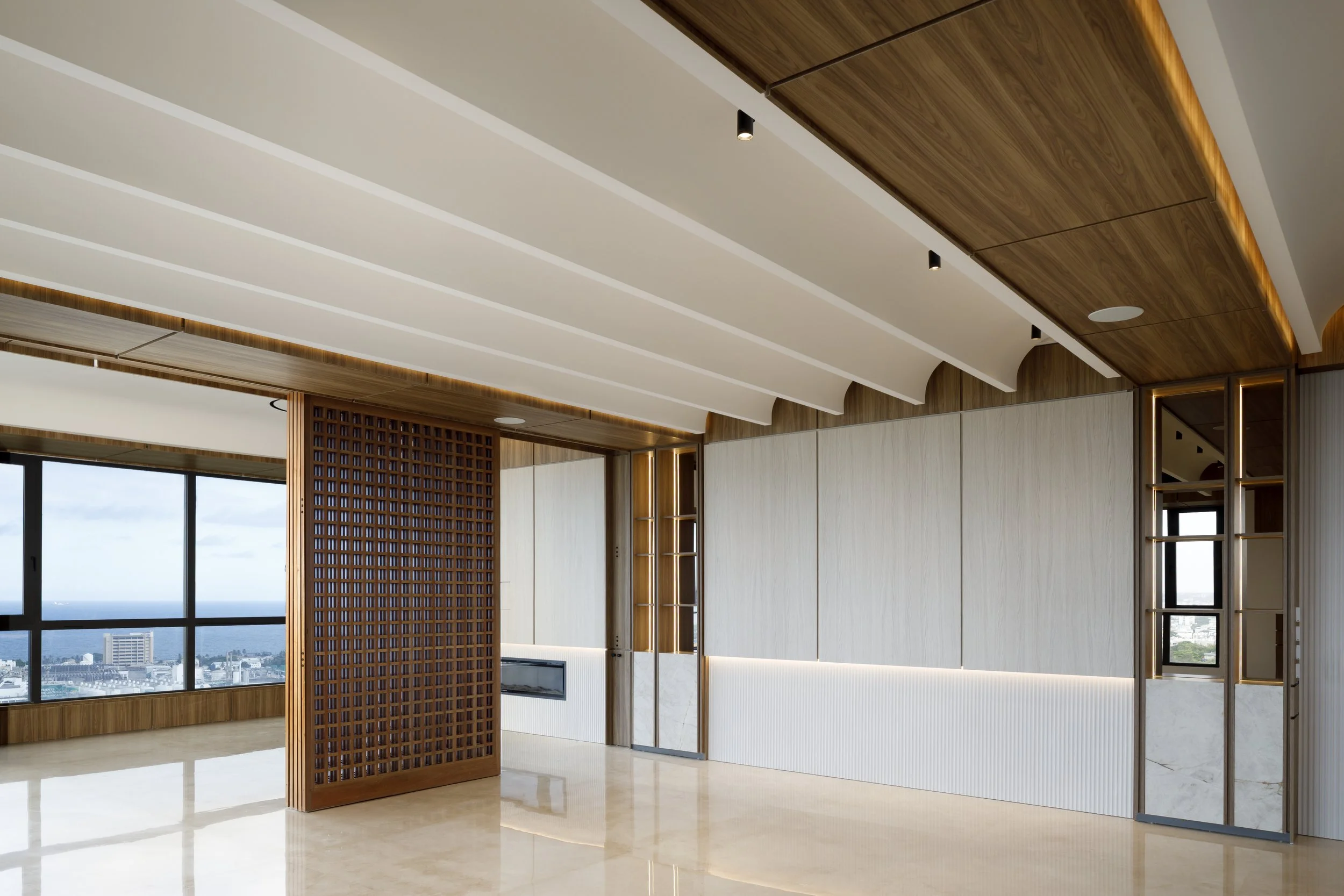 Interior moderno con techos curvos de madera y paredes blancas, grandes ventanas con vista a la ciudad y suelo de mármol brillante.