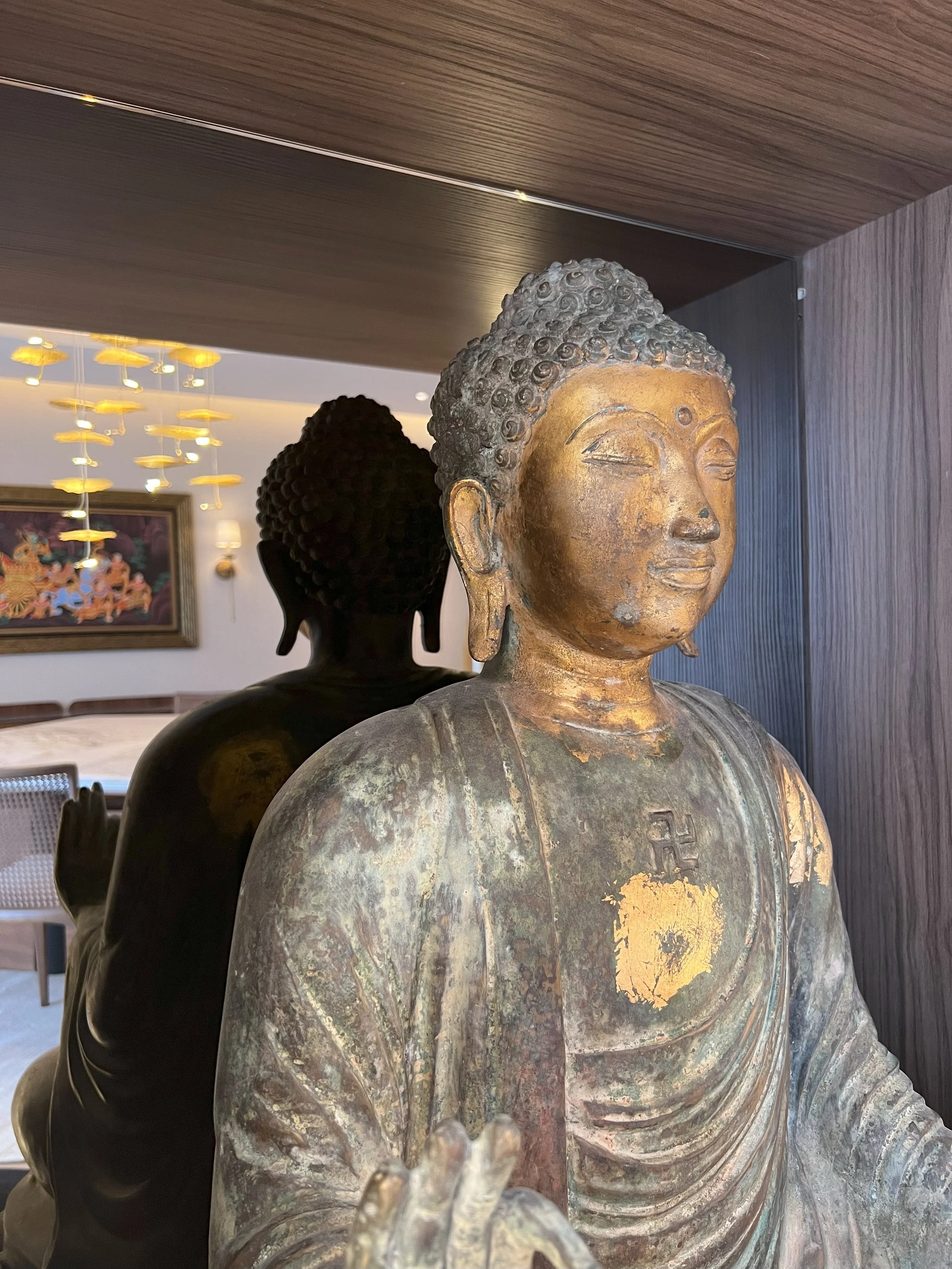 Esculturas de Buda con acabados oscuros y dorados en una composición decorativa interior.