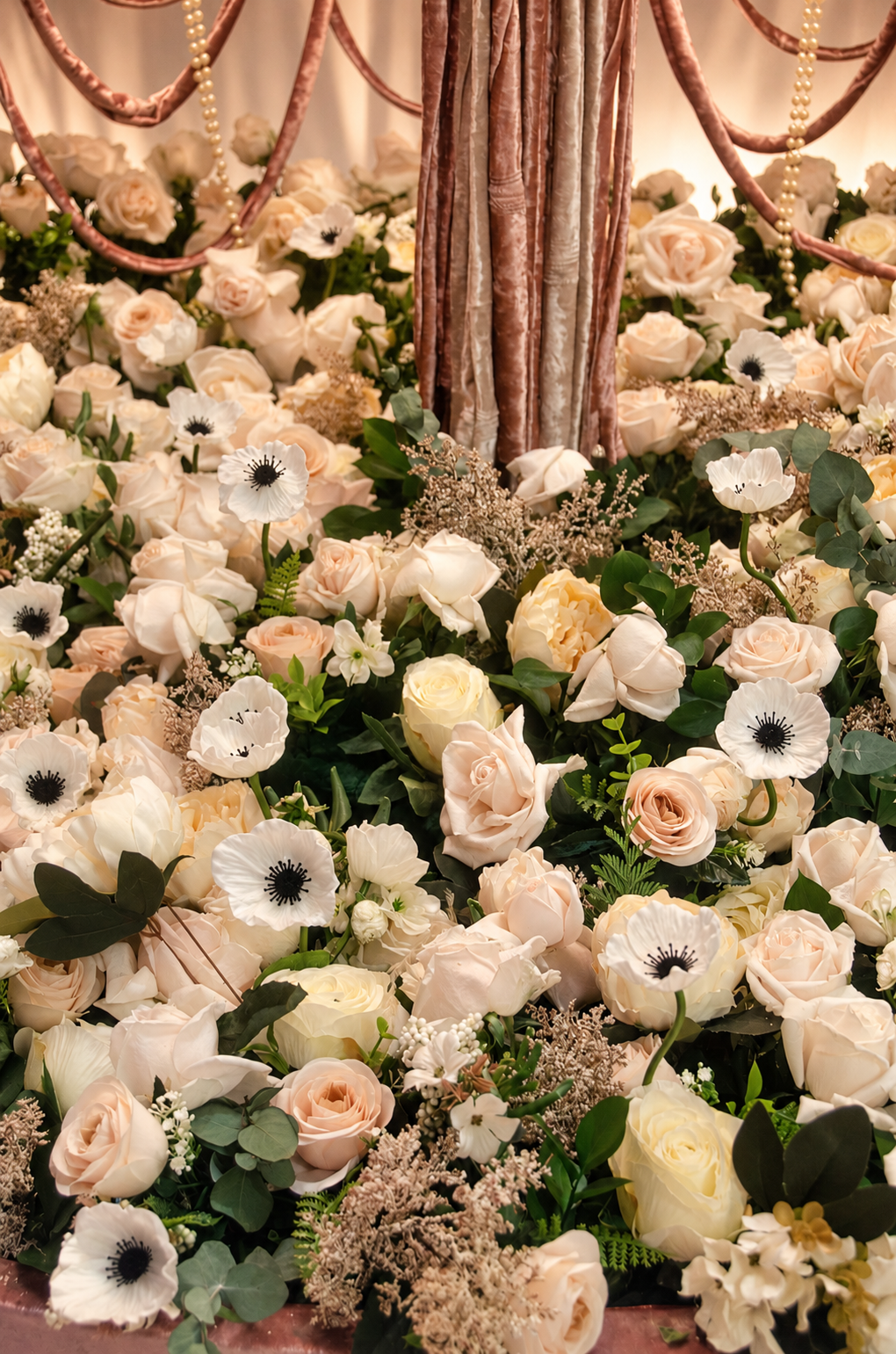 Detalle de rosas claras, anémonas blancas y follaje en la base del stand de Bridal Fashion Week 2024.