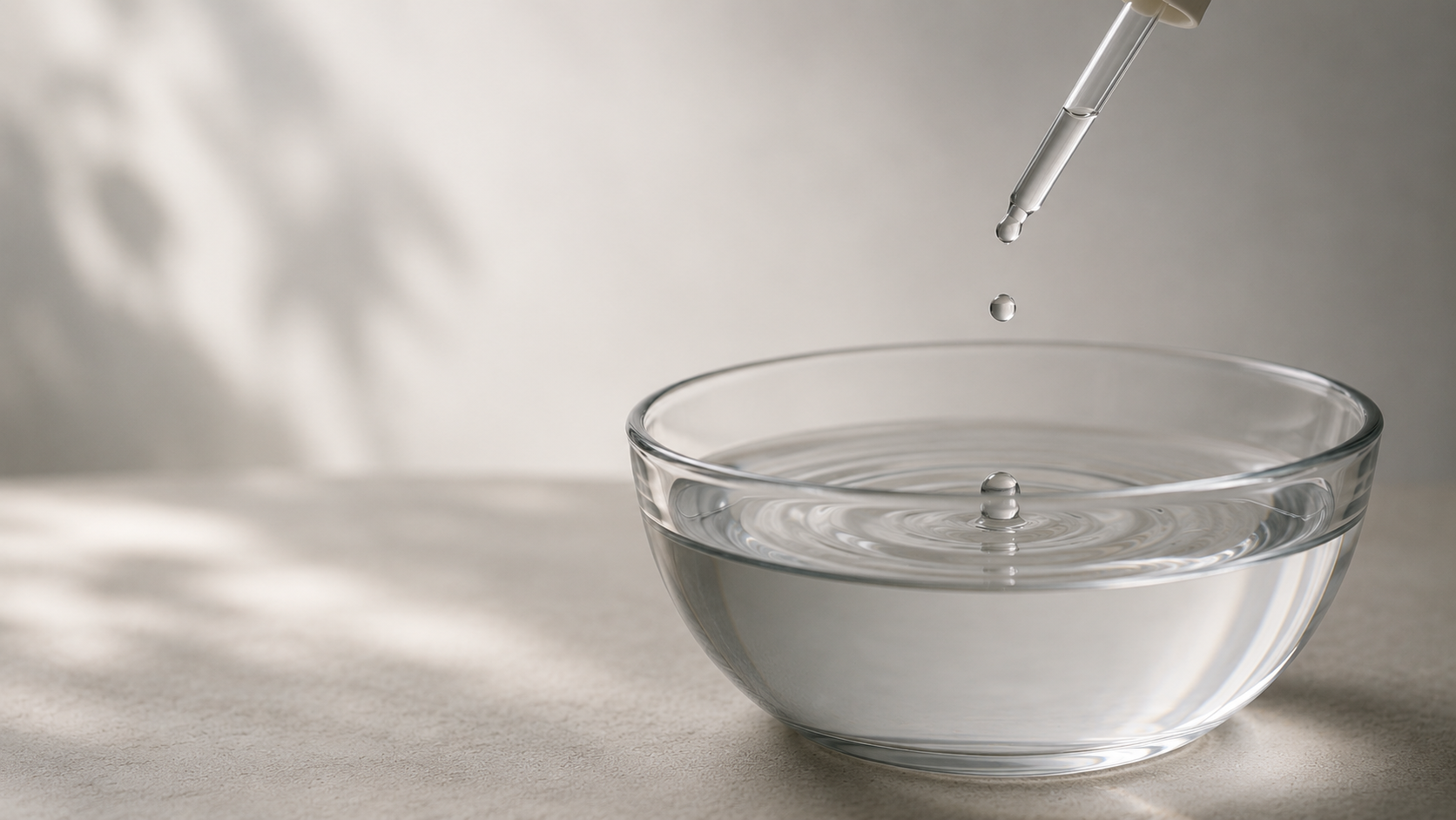 Close-up image of a droplet falling into a glass bowl of water, creating gentle ripples that evoke nervous system regulation, somatic awareness, and gradual therapeutic integration.