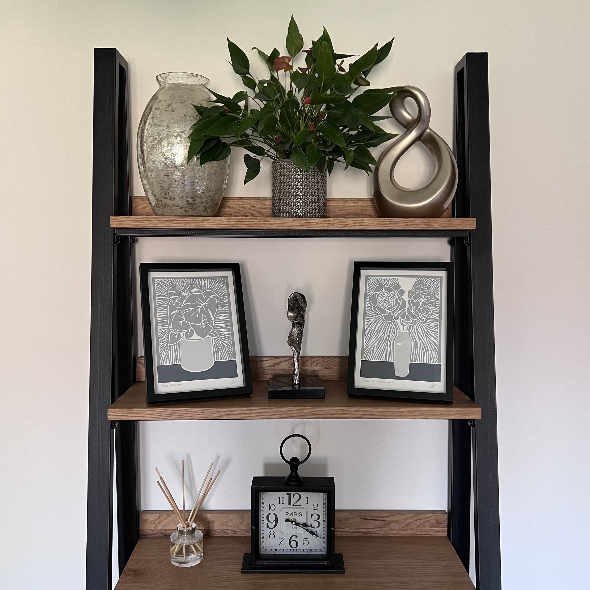 Artwork, plants and ornaments displayed on a wooden shelving unit