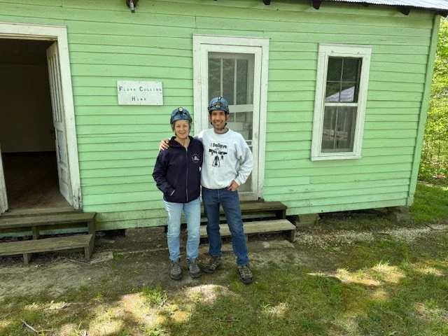 Picture of Author Nathan W. Landrum, and his mother outside of the Floyd Collins Home. Both are wearing hardhats with headlamps.
