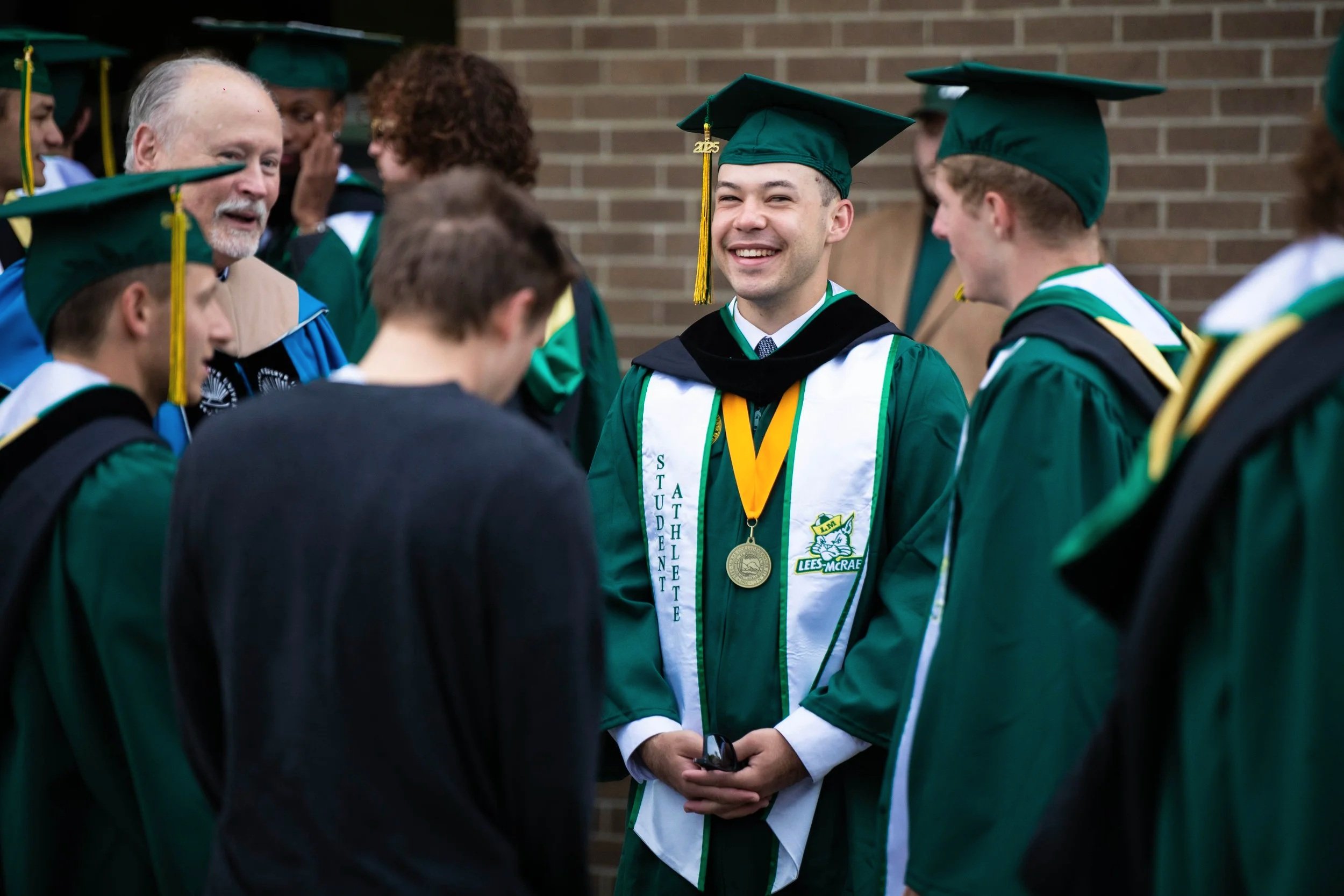 Graduation is always an exciting time of year
and 2025 was no exception. Graduates and
their families all gathered outdoors on Tate
Lawn. Pictured above is a group of graduates
sharing a laugh with their professor before the
ceremony got underway.