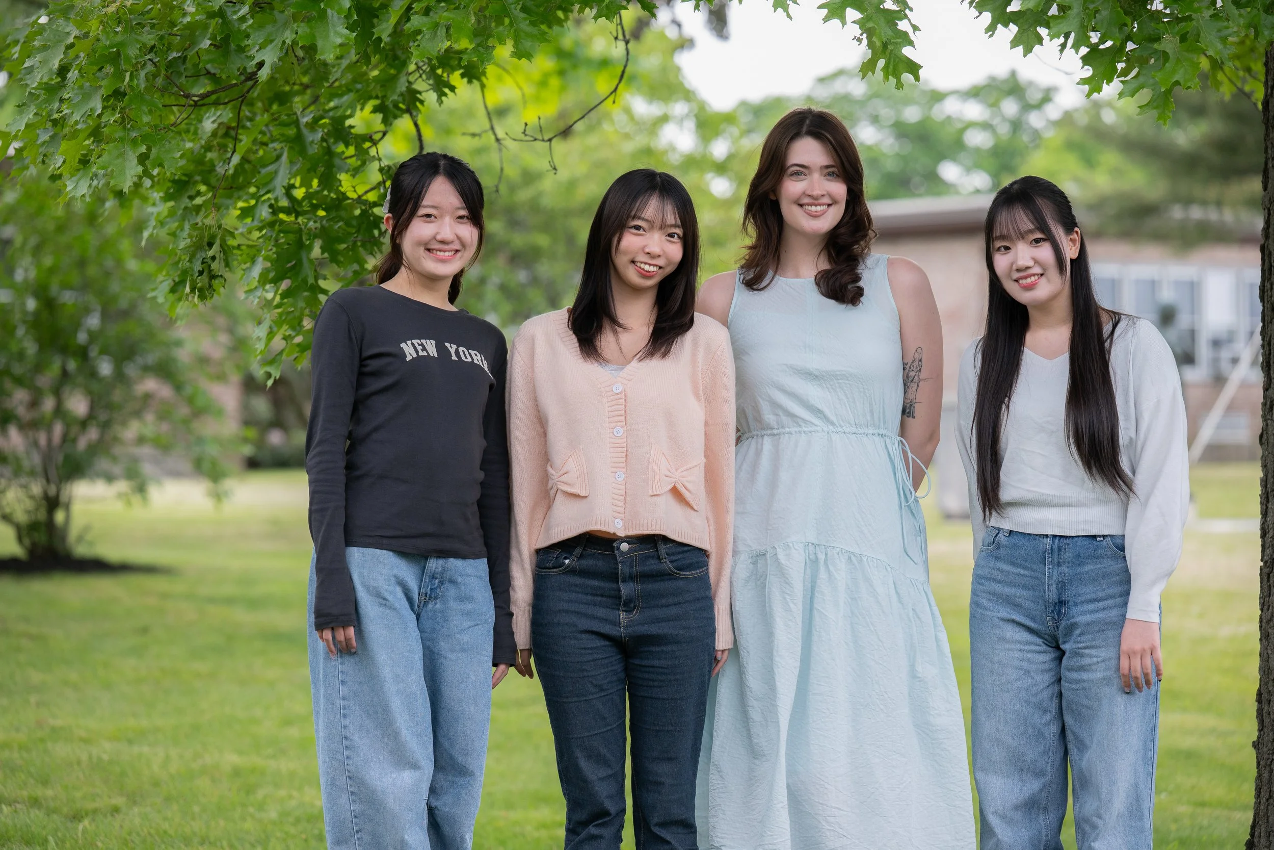 Four US and Japanese students playing a sanshin and looking at a music book.