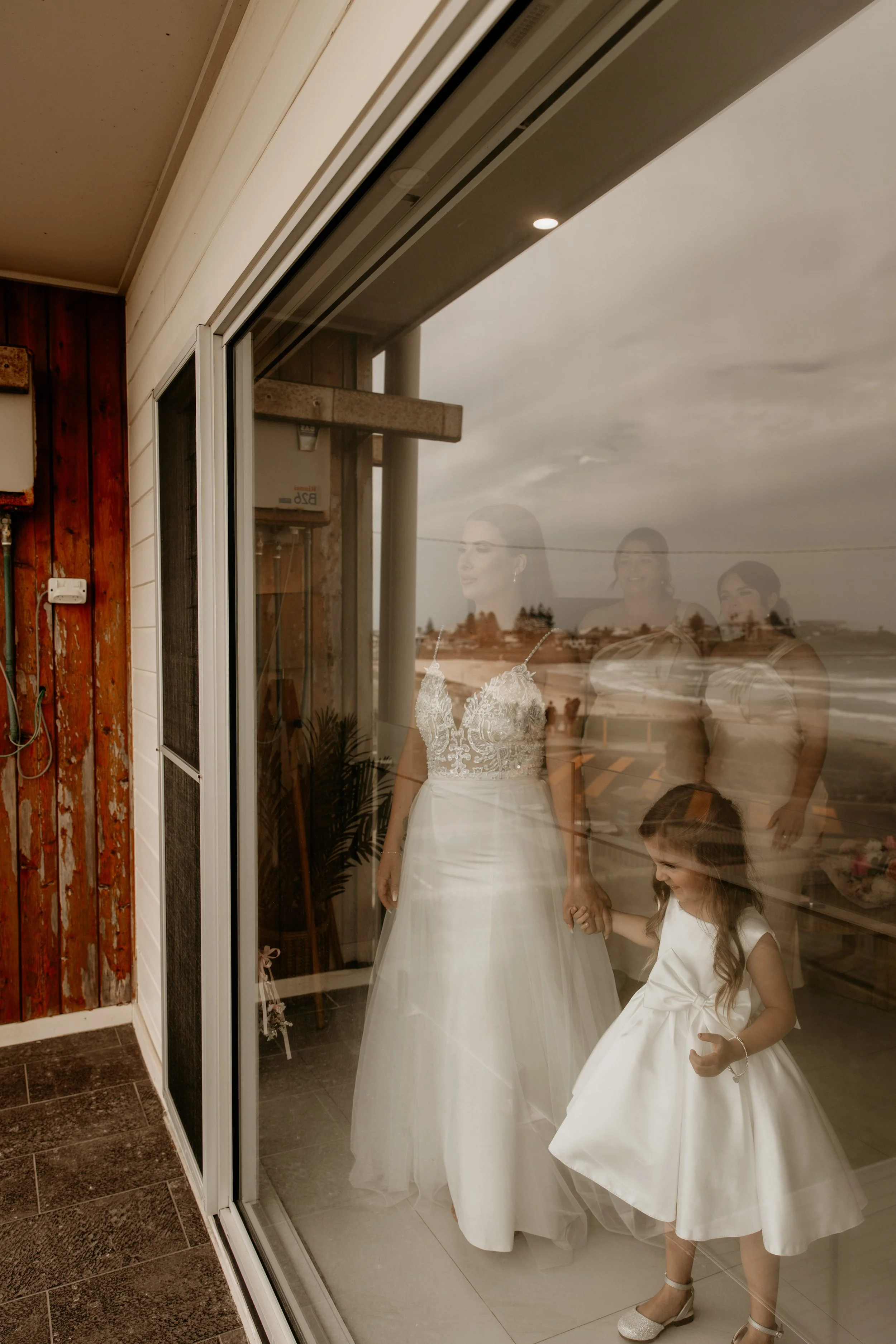 Reflection of a bride and young girl in a glass window.