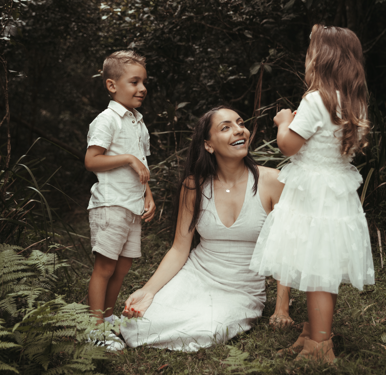 A woman sitting on the forrest floor engaging with her two children in a dedicated single parent photo shoot