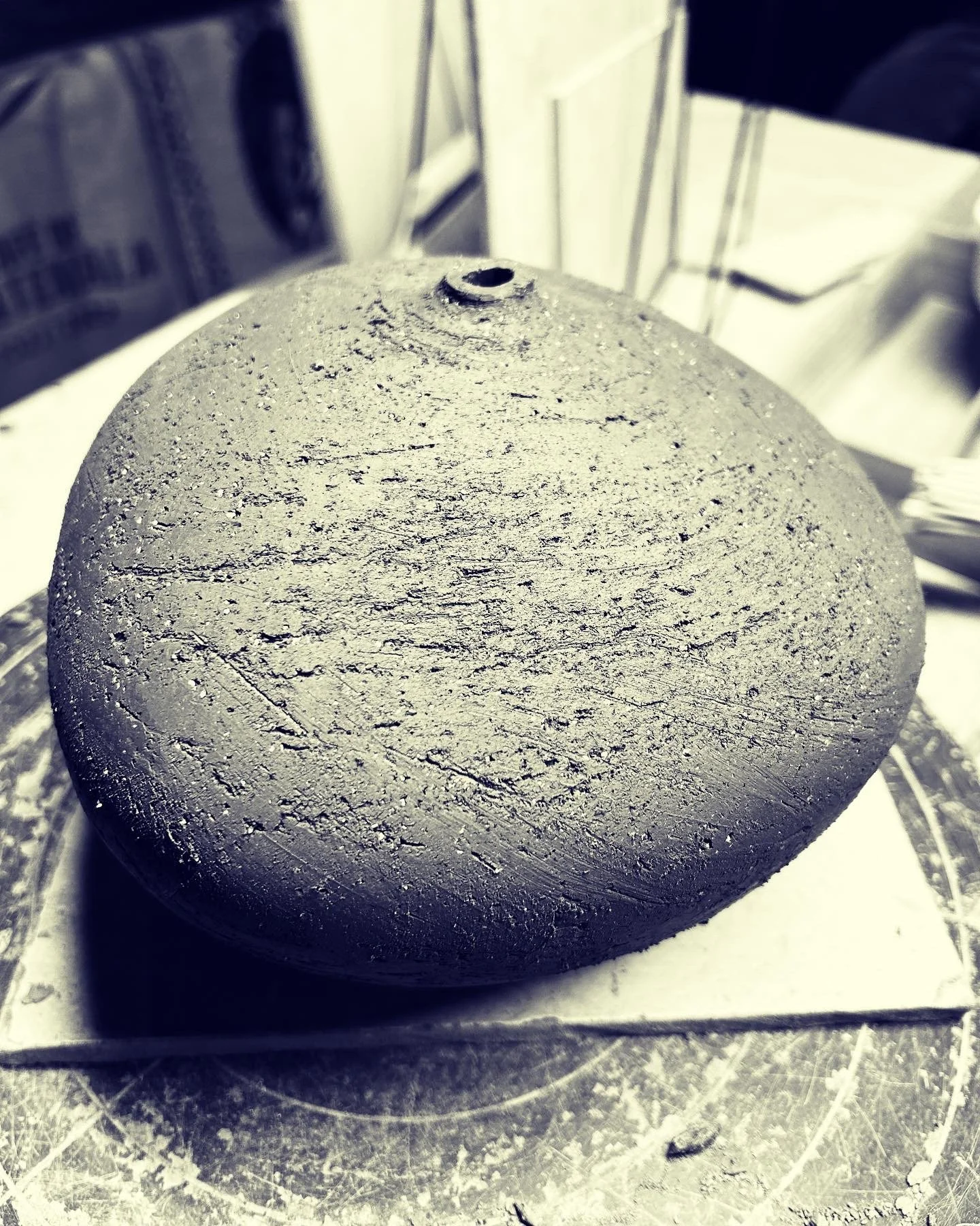 A large spherical rock with a rough, textured surface, possibly a meteorite or volcanic stone, resting on a cloth or paper surface.