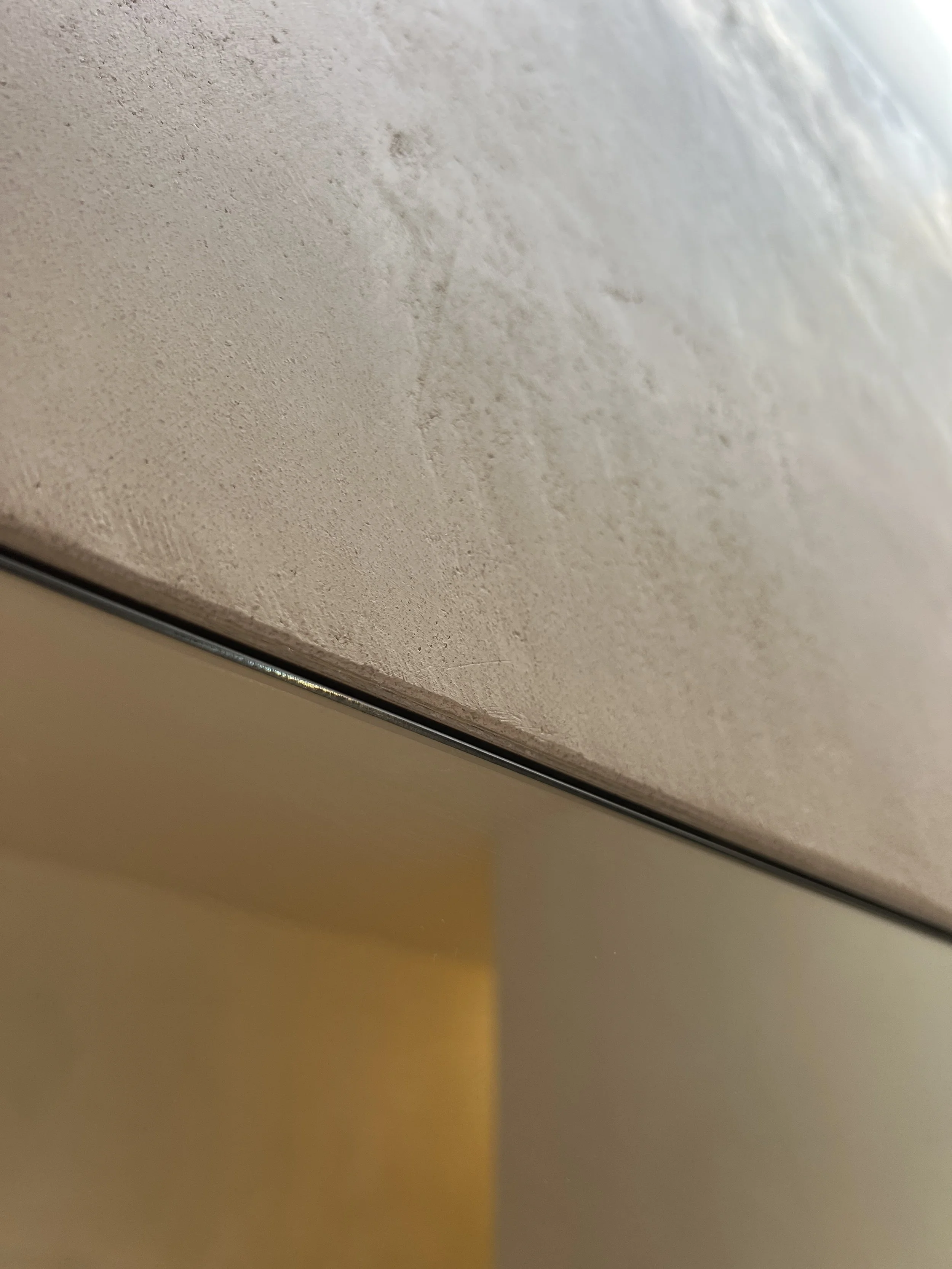 Close-up of a textured beige wall meeting a smooth light-colored surface.