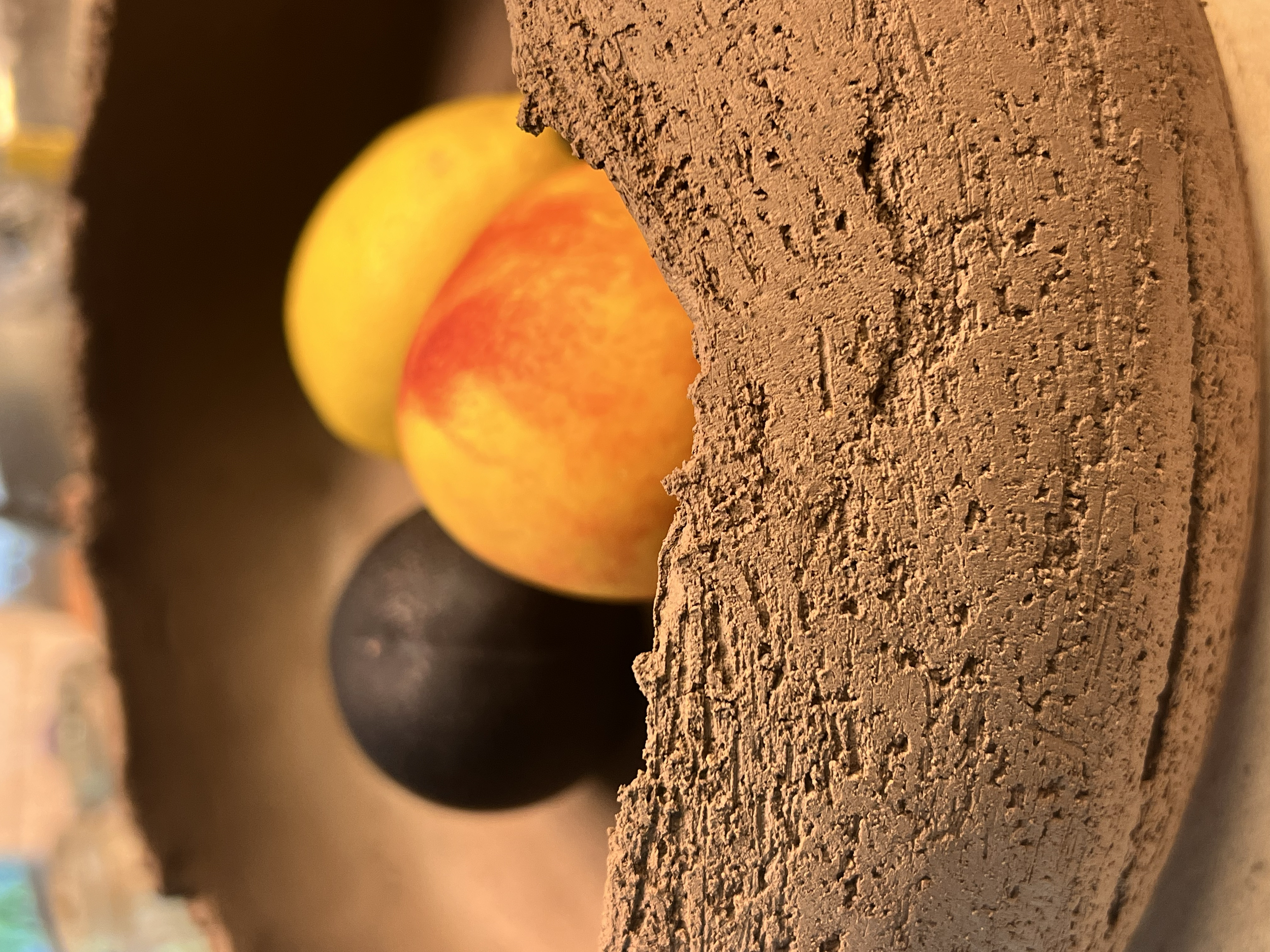 Three colorful balls, yellow, red, and black, are placed on a rough, textured stone surface, with a brick wall in the background.