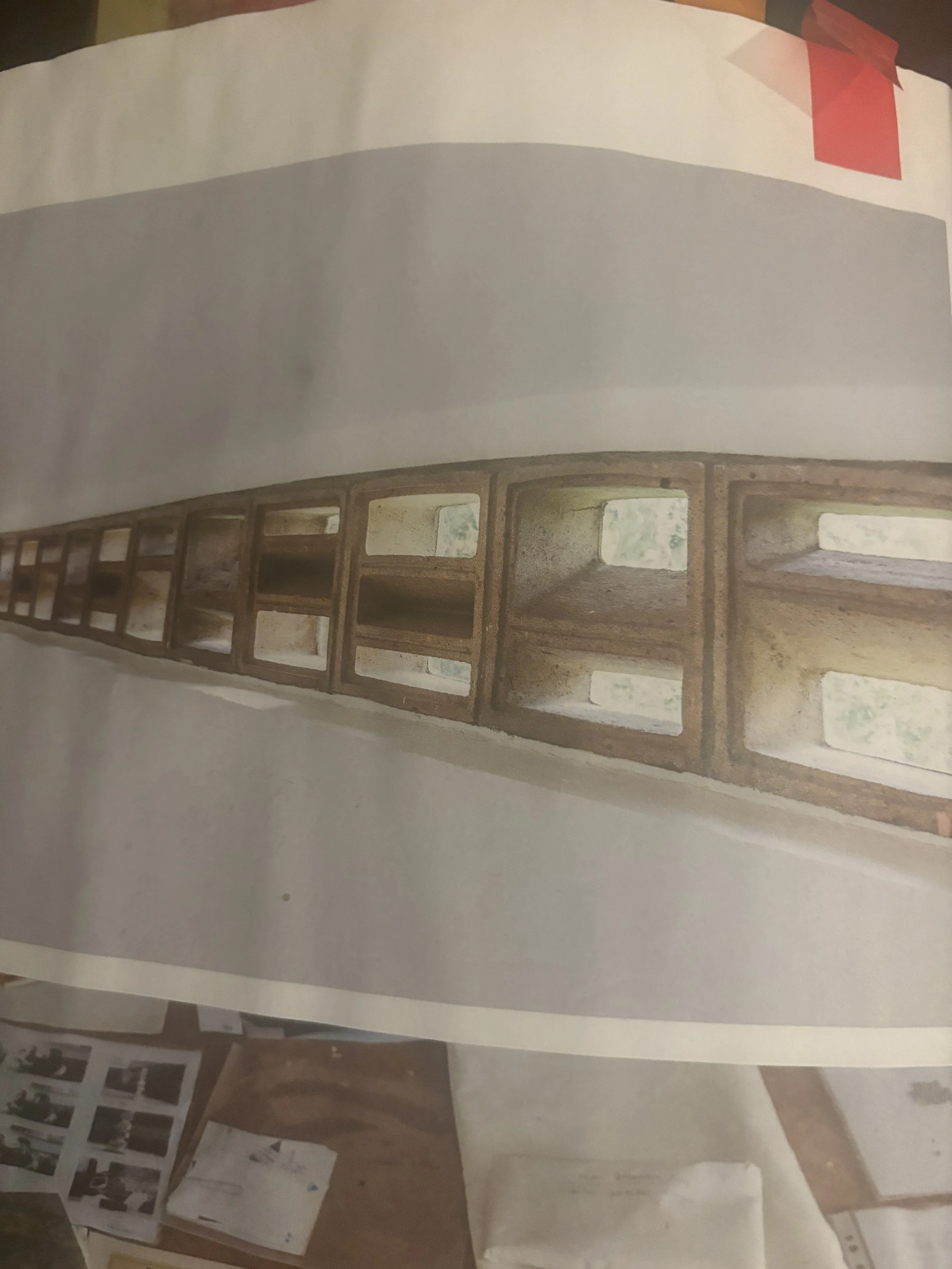 A wooden ladder leaning against a white wall, with a red ribbon tied to the top right corner of the wall.