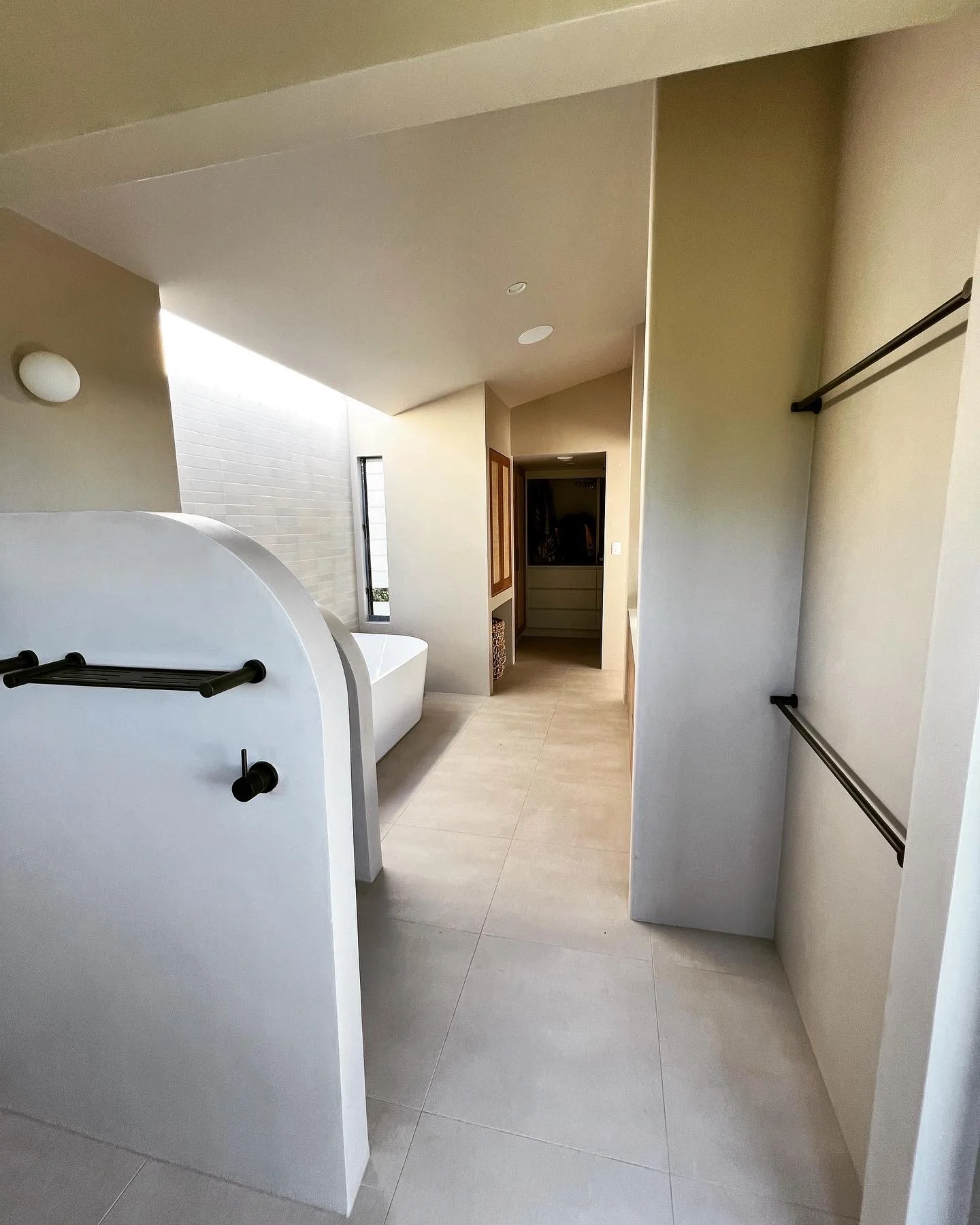 Modern bathroom with freestanding bathtub, beige tiles, and minimal decor.