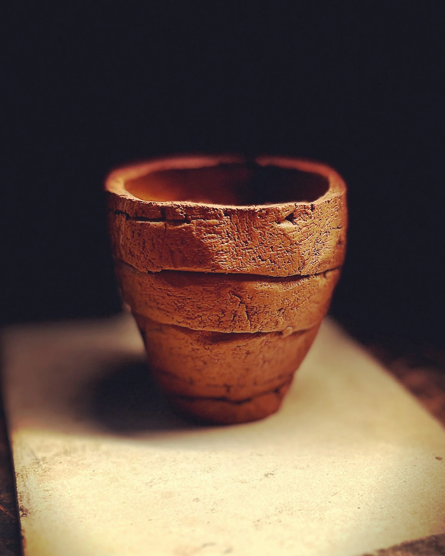Stacked small terracotta flower pots on a light-colored surface with dark background.