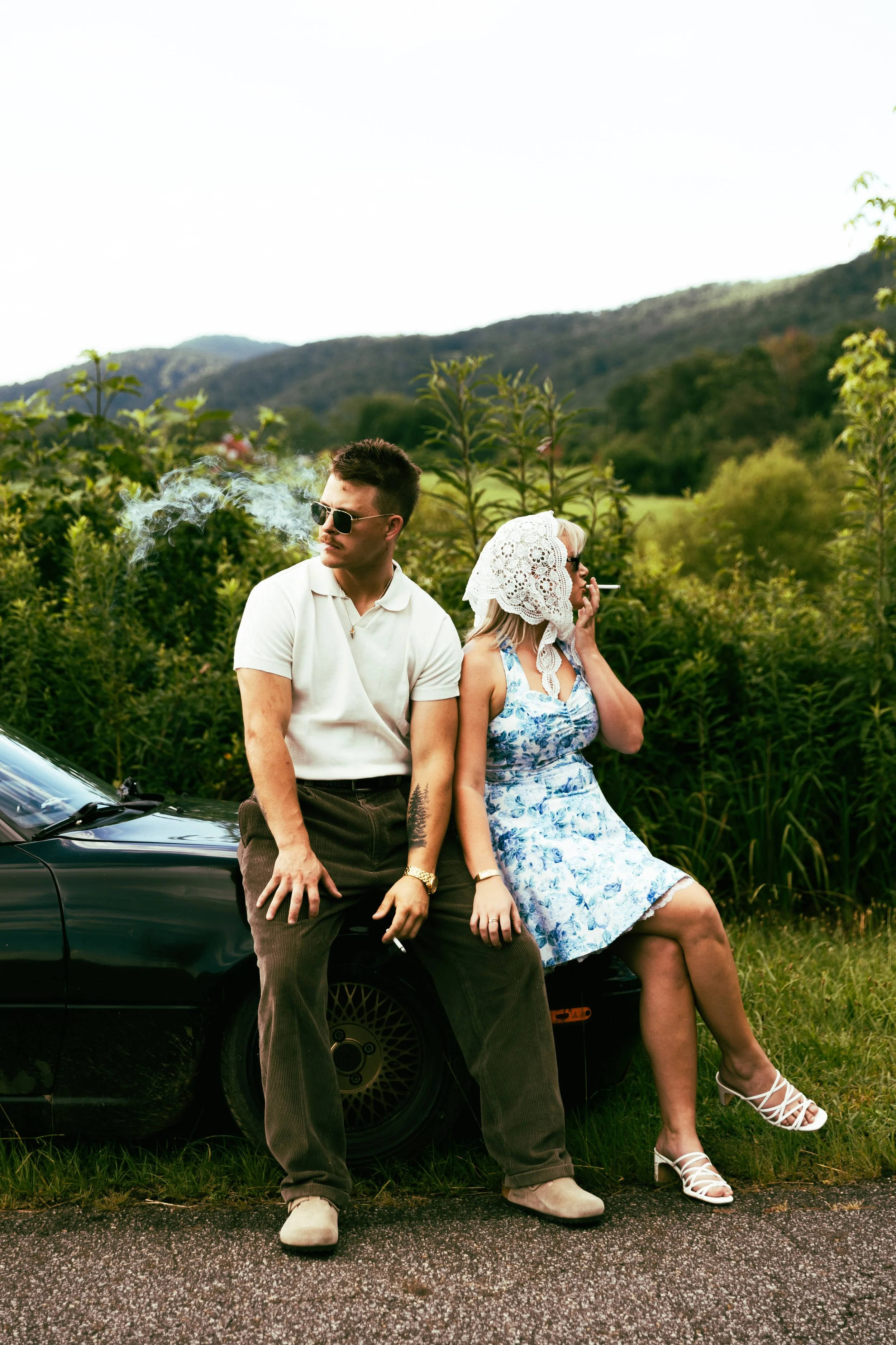 Couple smoking sitting on a car