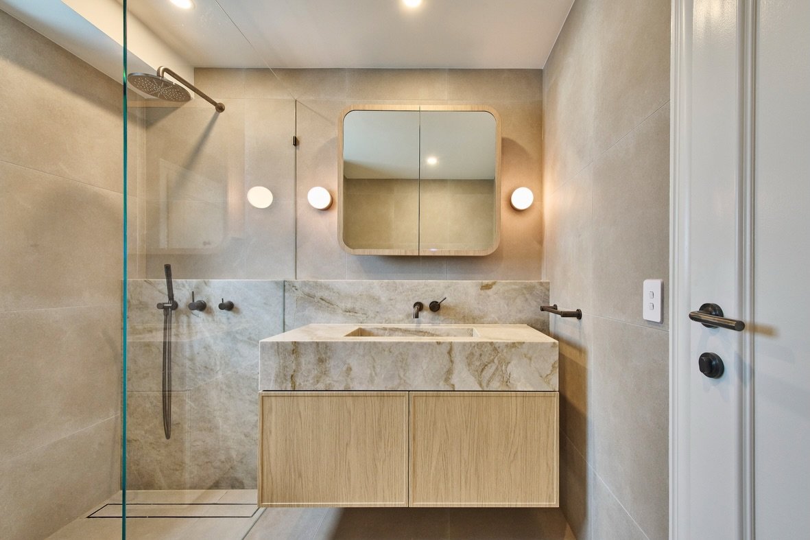 Before / After 
Our key moves to create a new bathroom for our client 

1. Warm tones, timeless materials such as natural stone with mat finishes 

2. Layered lighting (down light snd wall light)

3. Better floor falls for drainage

4. Exhaust fan to