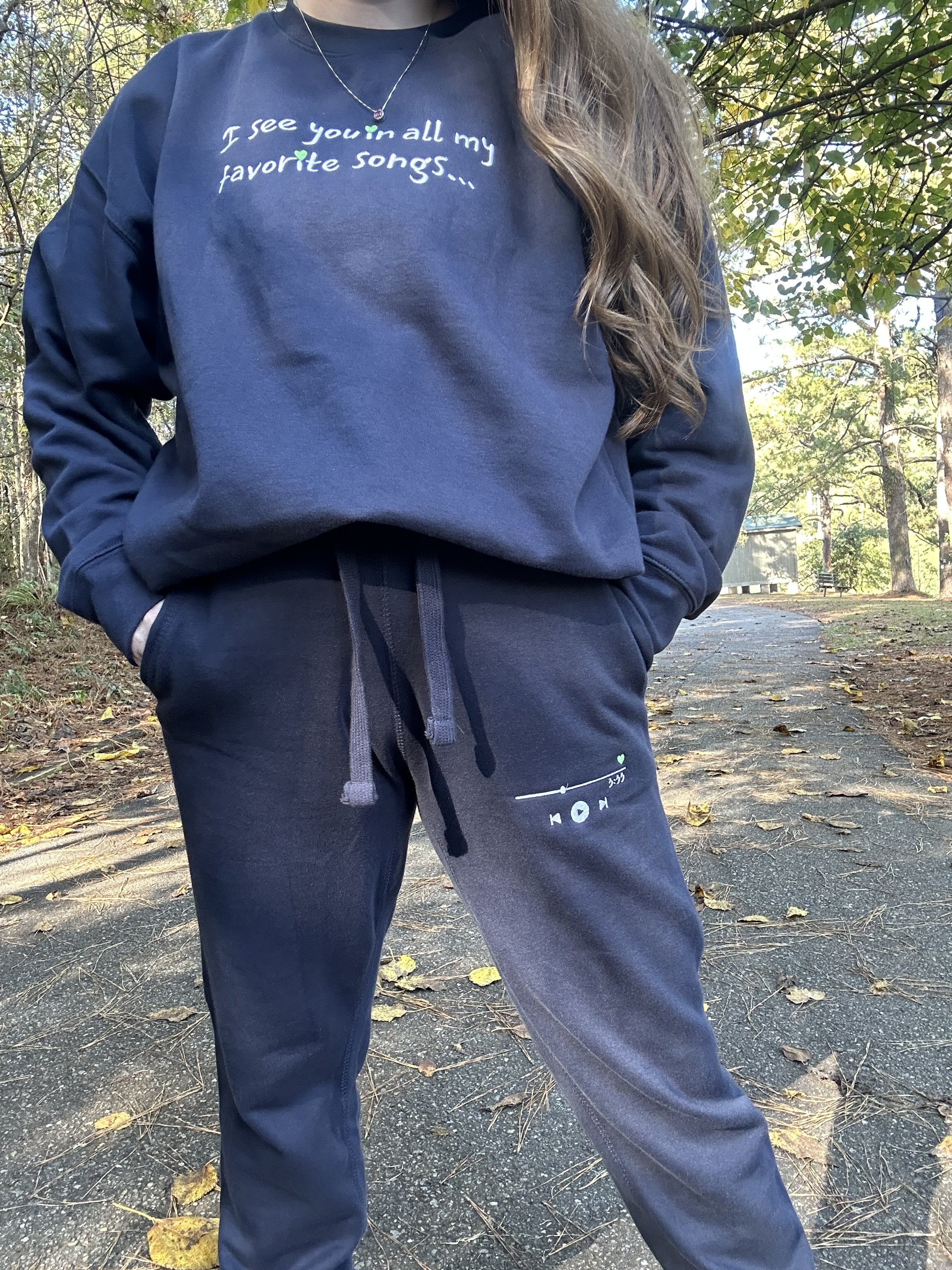 Close up of navy blue sweat set modeled by a young brunette woman. You can see the thick material, adjustable drawstrings, and front jogger pockets