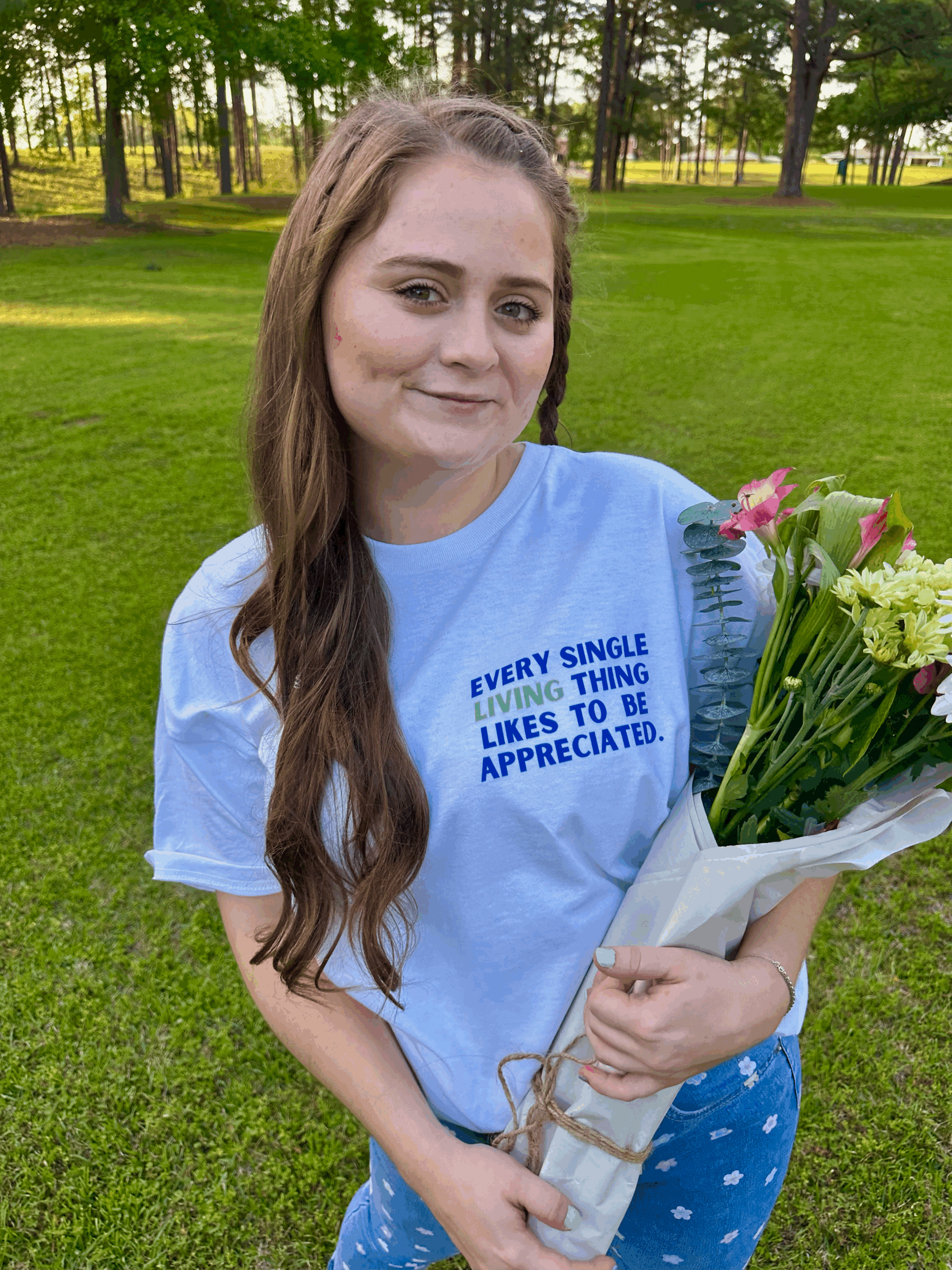 Waist up photo of same woman modeling the new tshirt. Would you wear a pair of denim pants with tiny flowers on them? We sure would! and we love pairing it with our newest shirt