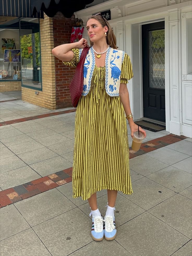 blue and white floral vest styled over a green striped midi dress