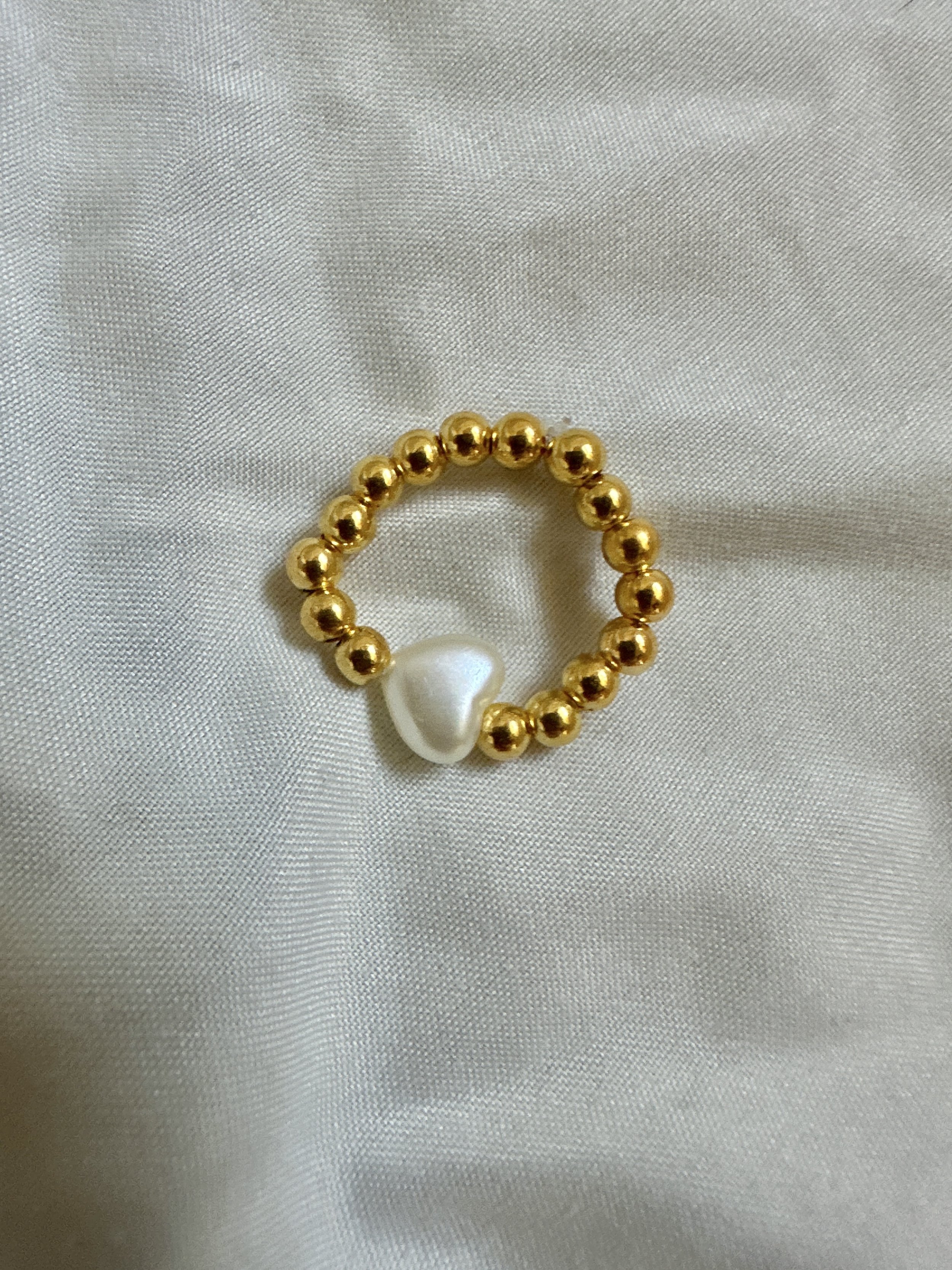 a heart shaped pearl with gold beads stretch ring for women
