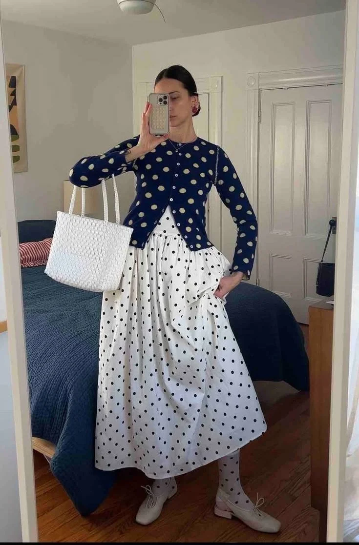 what and black polka dot dress with a polka dot cardigan layered on top of it. with white kitten heels and a white tote purse
