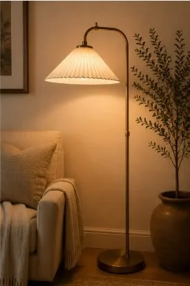 a cozy corner in the living room with a chair, fuzzy throw blanket, a standing lamp, and a plant in the corner