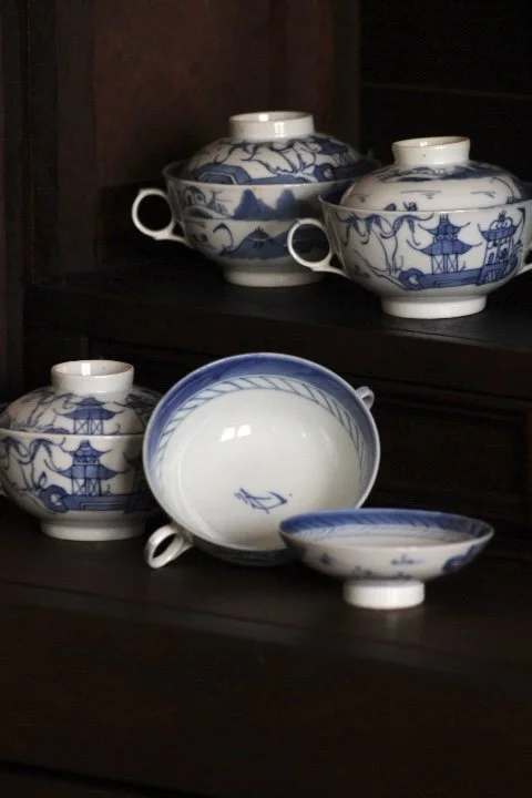 Set of blue and white porcelain teapots and bowls on a dark wooden shelf.