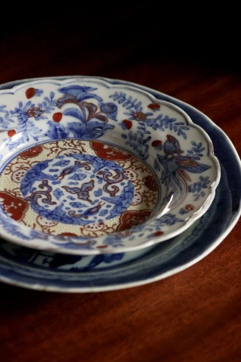 Stack of three Chinese porcelain bowls with blue and red intricate floral and bird patterns on a wooden surface.