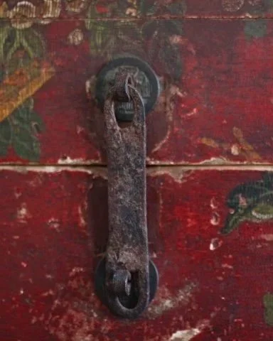 Close-up of an old, rusty latch or handle on a weathered, painted wooden door or surface.