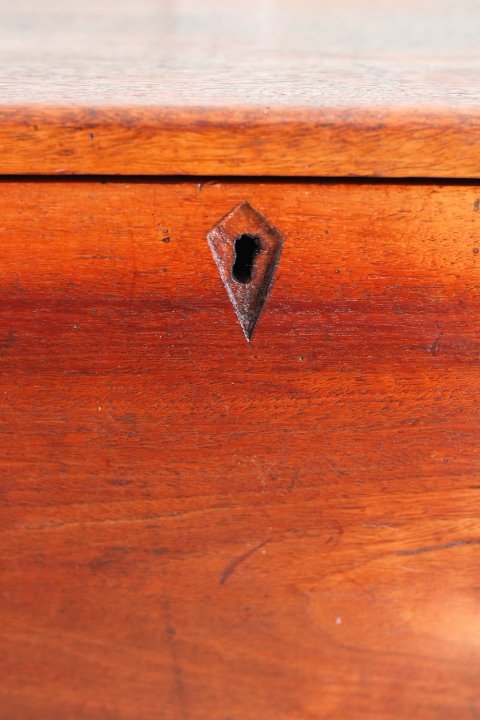 Close-up of a wooden surface with a small, old keyhole or lock on it.