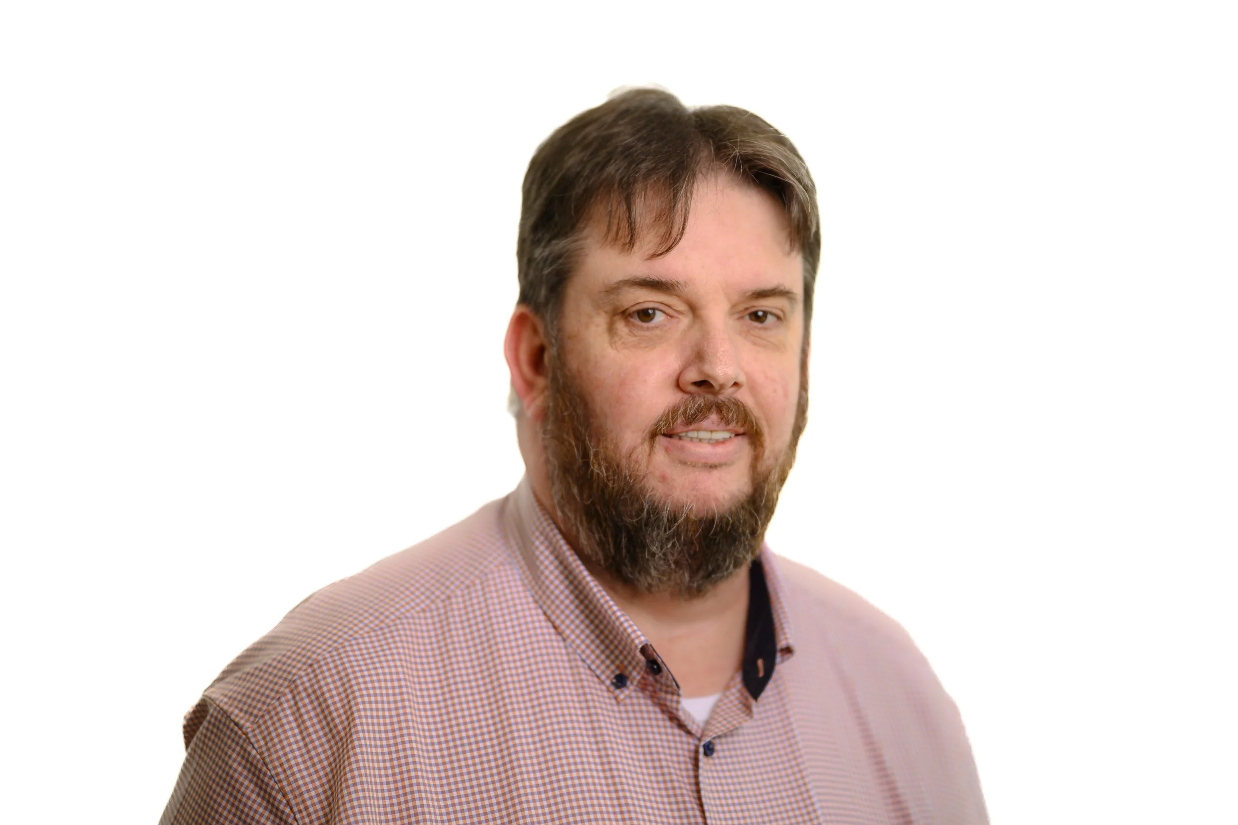 A man with a beard and brown hair wearing a checkered shirt looking at the camera against a white background.