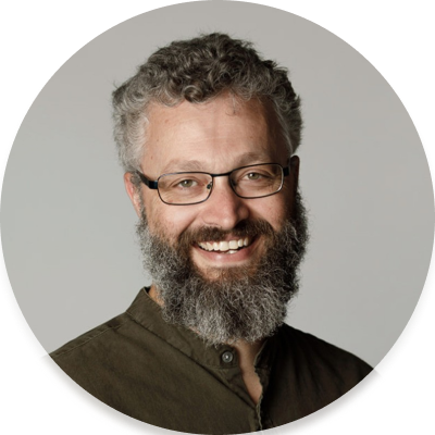 Joshua is a middle aged man with beard, wearing a green shirt and glasses.