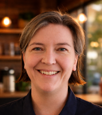 Karen is a middle-aged Caucasian woman, who light brown shoulder length hair. She is wearing a navy top & smiling at the camera.